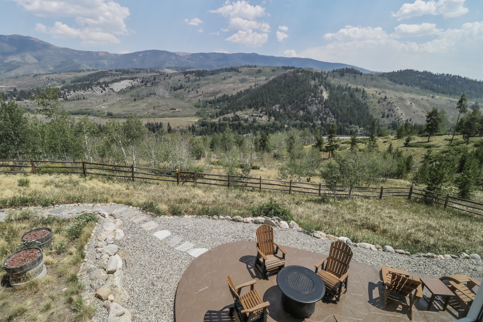 A peaceful mountain retreat set against rolling hills and forested peaks, with a private fire pit gathering area waiting for your evening under the stars.