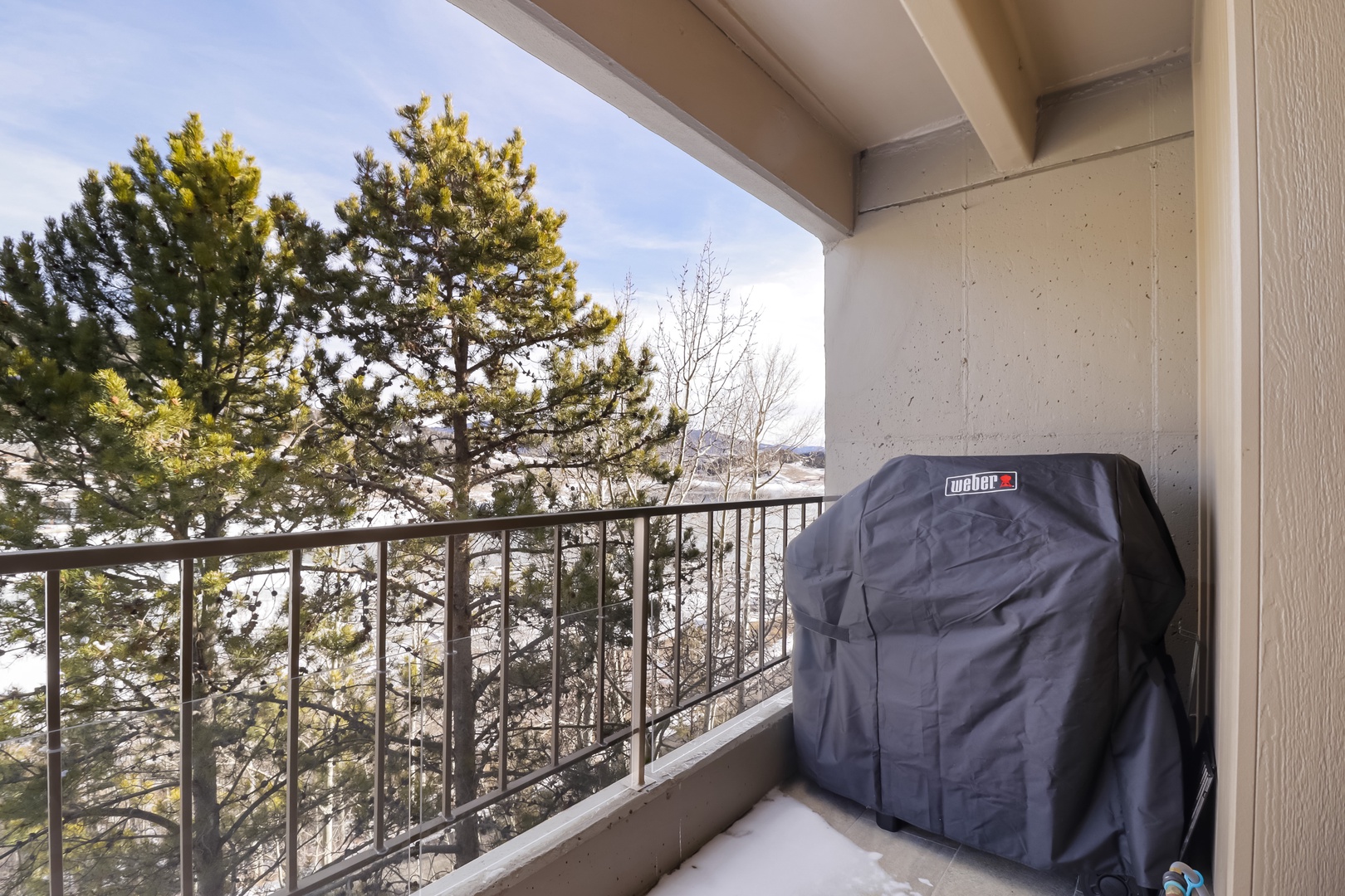 Your covered balcony features a Weber grill for outdoor cooking with scenic mountain views beyond.