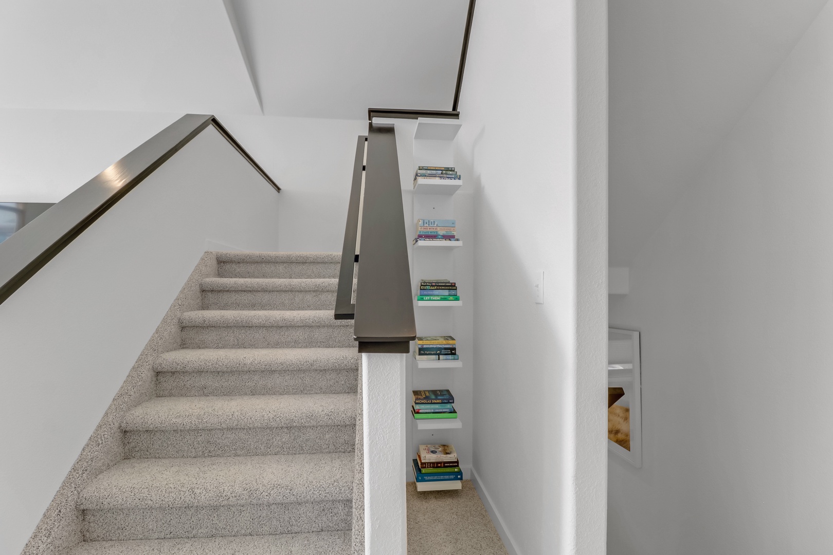 Climb these modern stairs to discover your upper-level retreat, with a charming book nook tucked beneath for cozy reading moments.