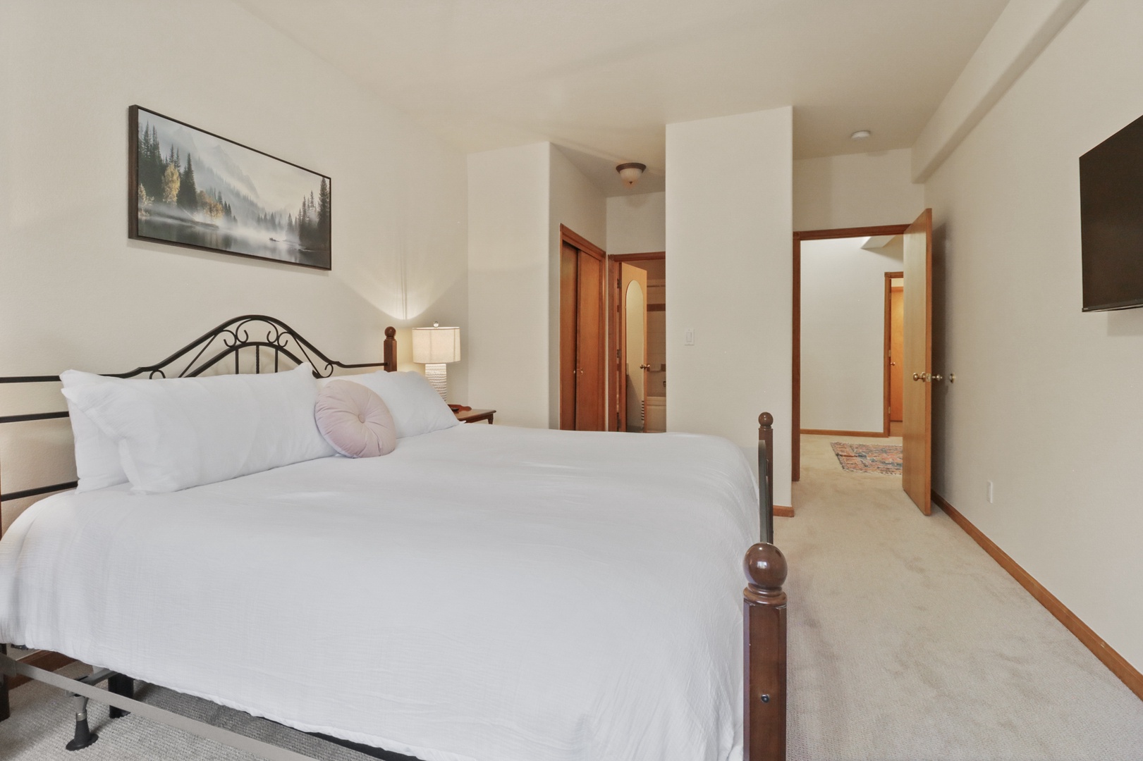 Drift off in your elegantly appointed bedroom, featuring crisp linens and peaceful mountain artwork that sets the tone for restful nights.