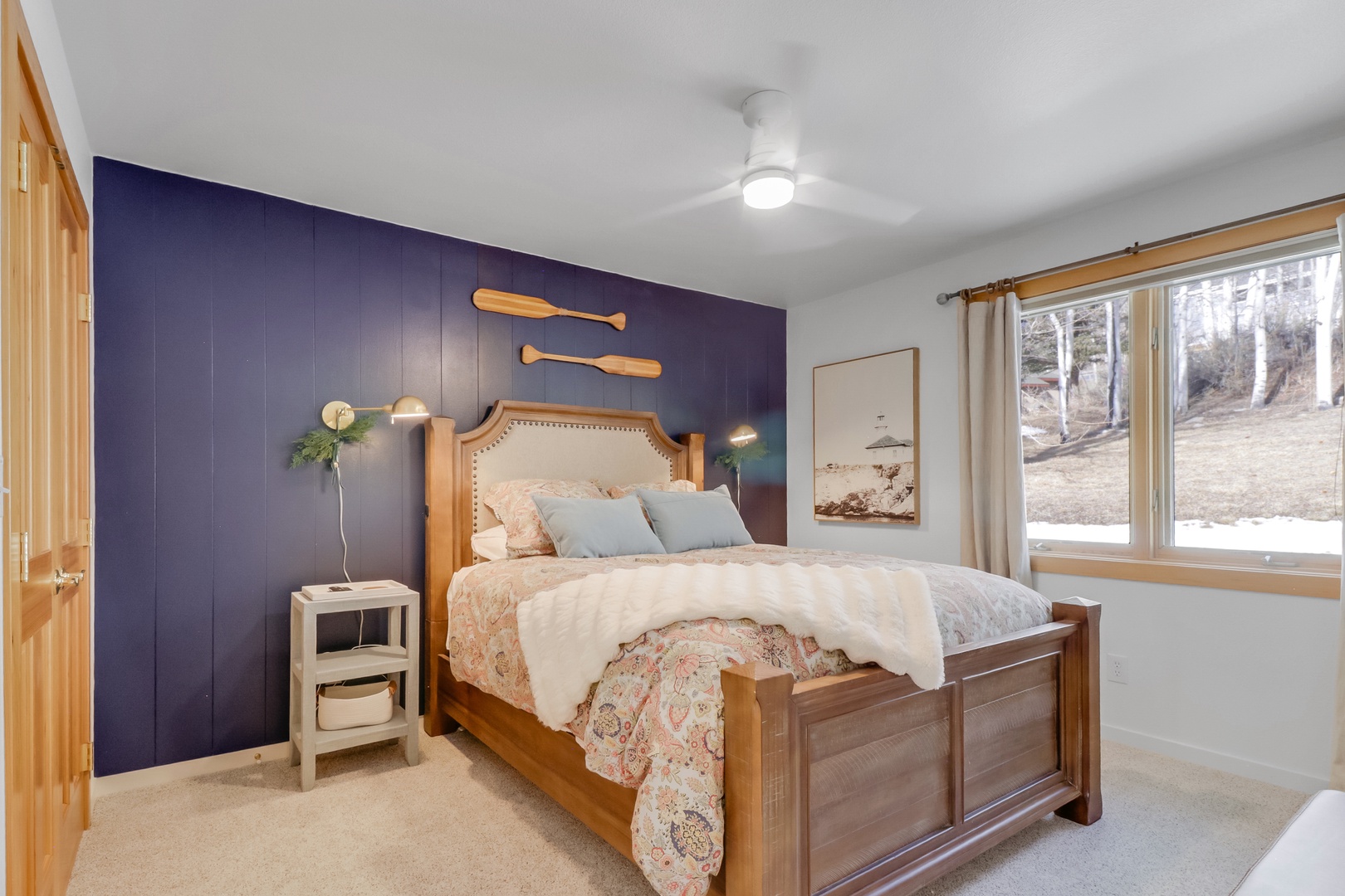 Sink into this cozy bedroom with its striking navy accent wall and warm wood touches. Natural light streams through large windows while comfortable bedding awaits your restful stay.