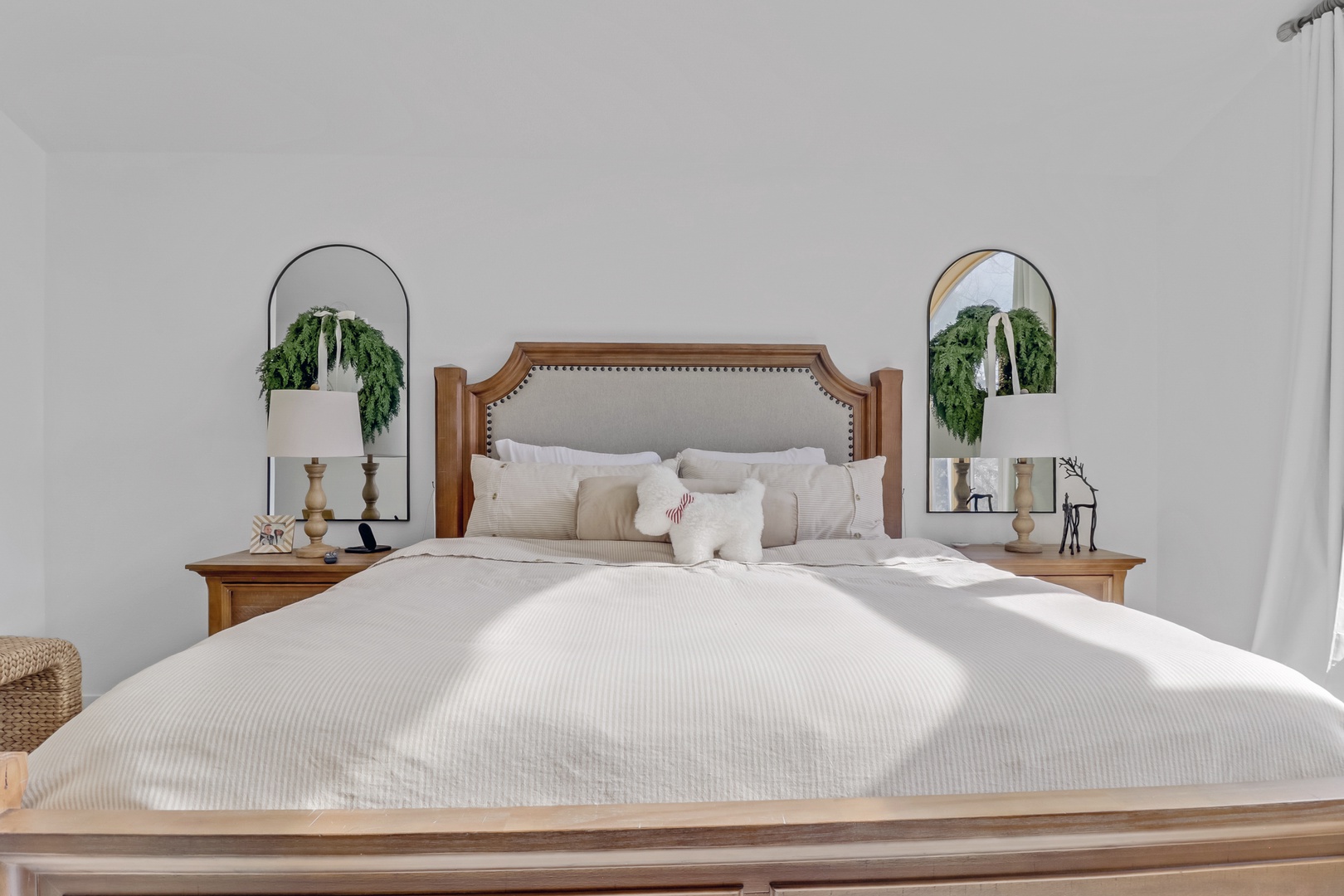 Sink into crisp white linens and plush pillows in this serene bedroom, where natural sunlight and thoughtful touches create your perfect retreat.