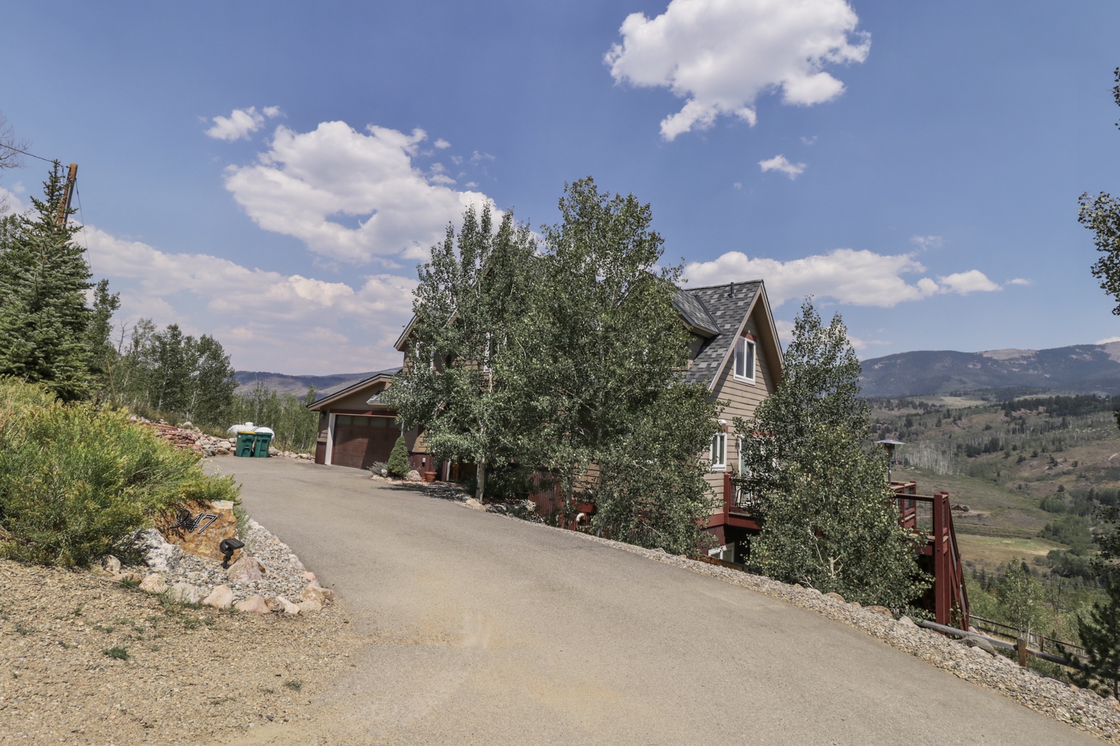 A charming mountain property nestled among tall trees and rolling hillsides, featuring a welcoming driveway and private garage for your convenience.