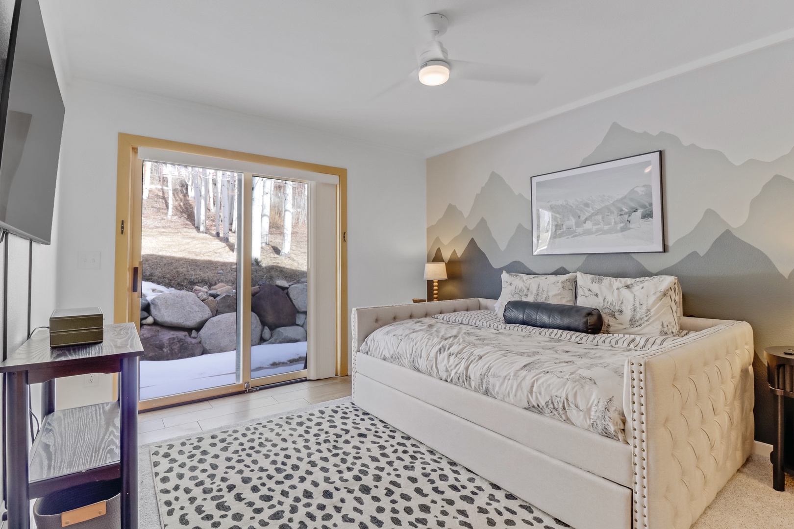 Unwind in your serene bedroom with mountain-inspired decor and peaceful forest views through sliding glass doors.