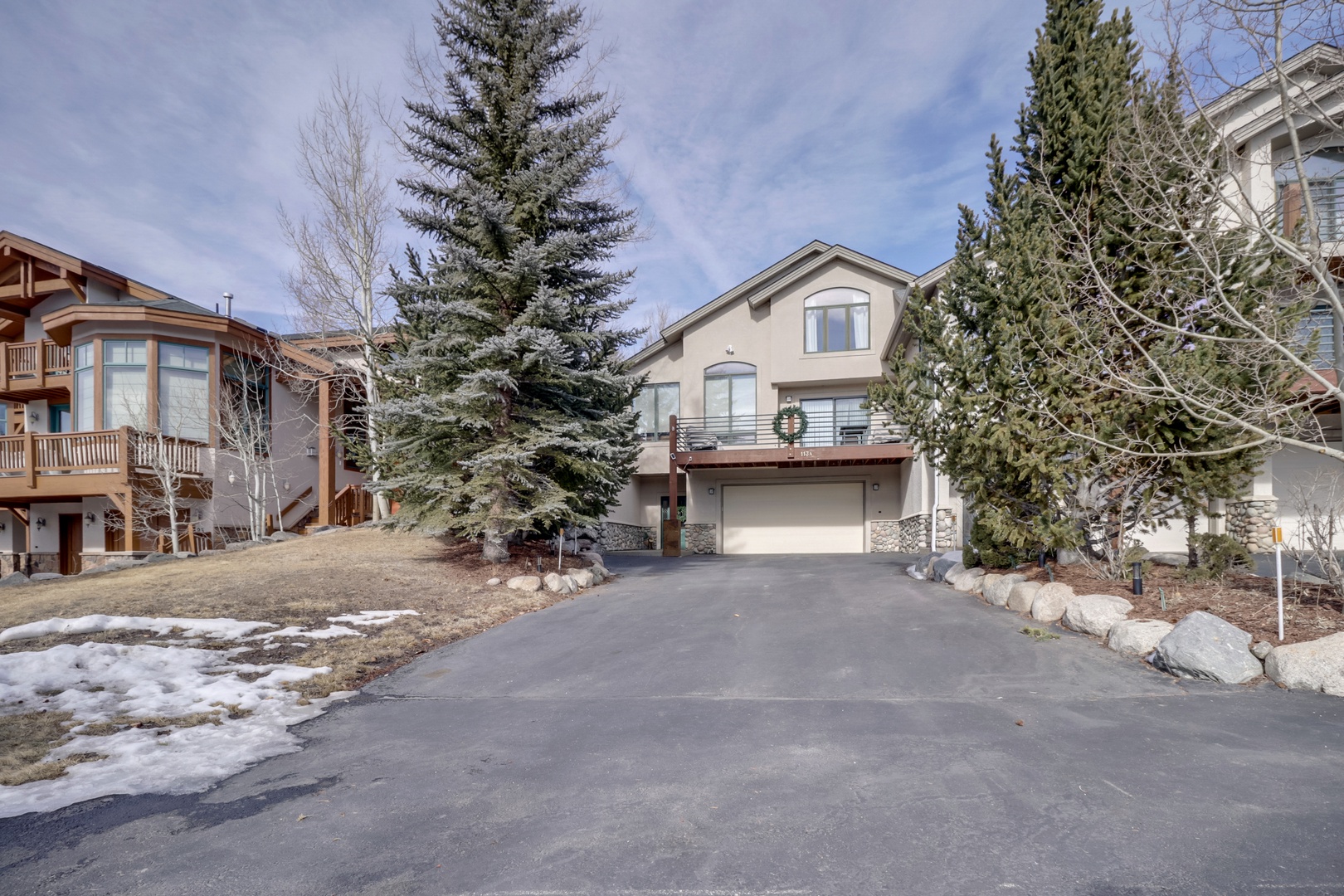 Charming mountain home nestled among towering evergreens with convenient driveway parking and peaceful neighborhood setting.