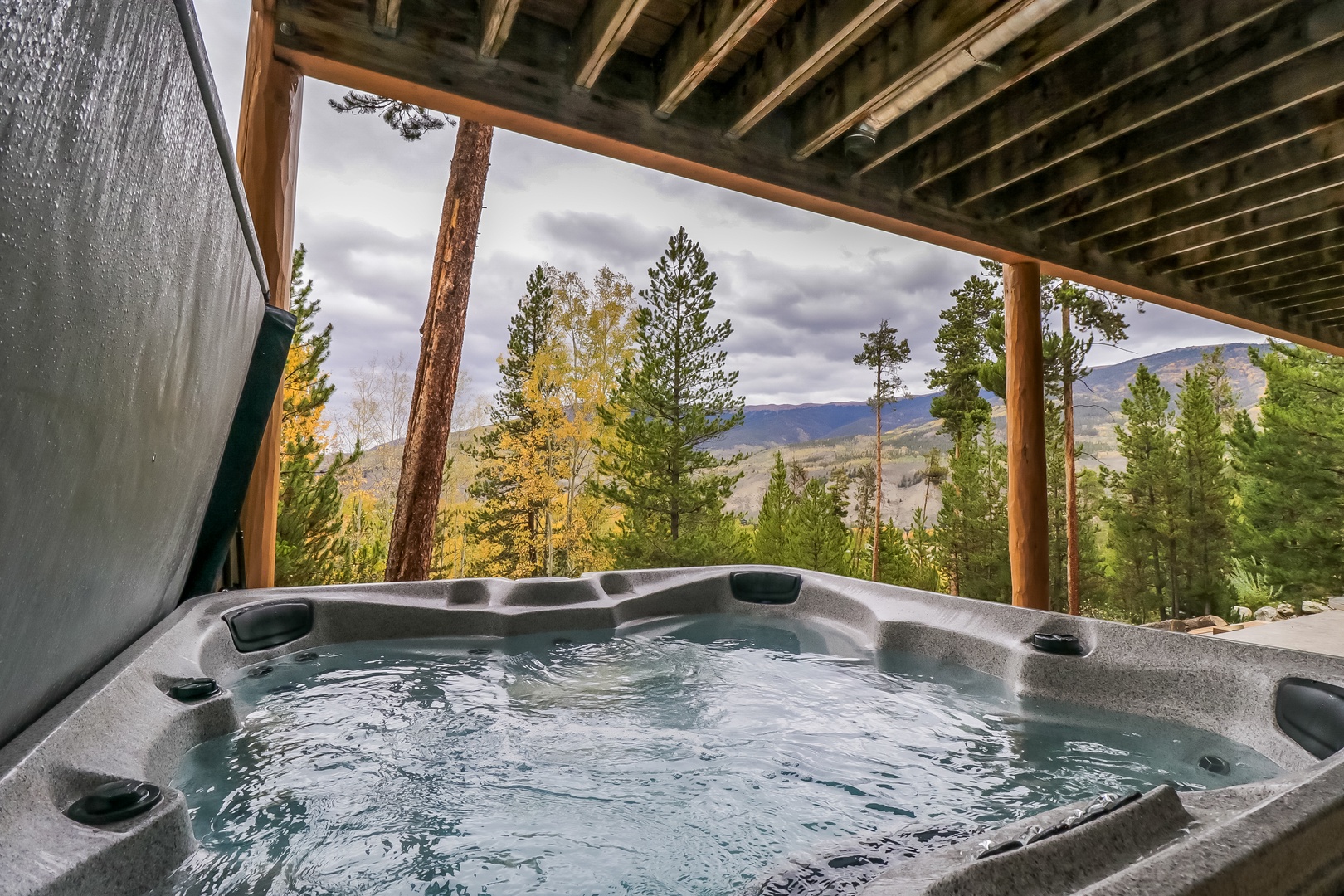 Soak in the hot tub under a sheltered deck as you drink in stunning mountain vistas framed by towering pines—your perfect retreat awaits.