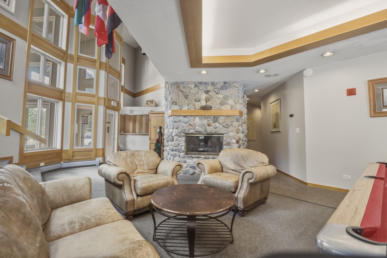 Gather around the stone fireplace and sink into plush armchairs—your alpine retreat awaits with soaring ceilings, natural light, and timeless mountain charm.