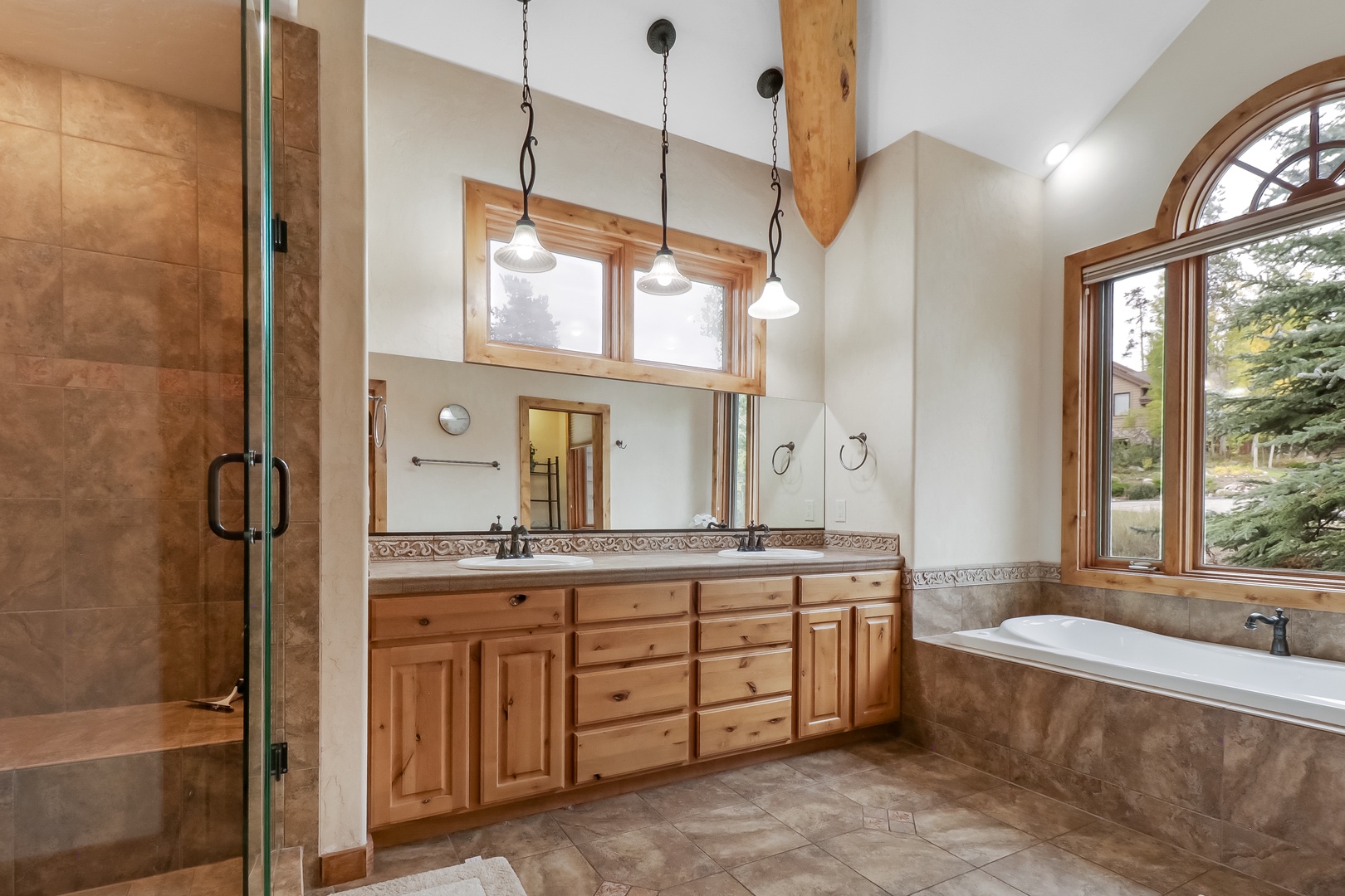 Step into your spacious spa-like retreat with soaring vaulted ceilings, a luxurious soaking tub framed by natural light, and a beautiful glass-enclosed shower—your private sanctuary for unwinding.