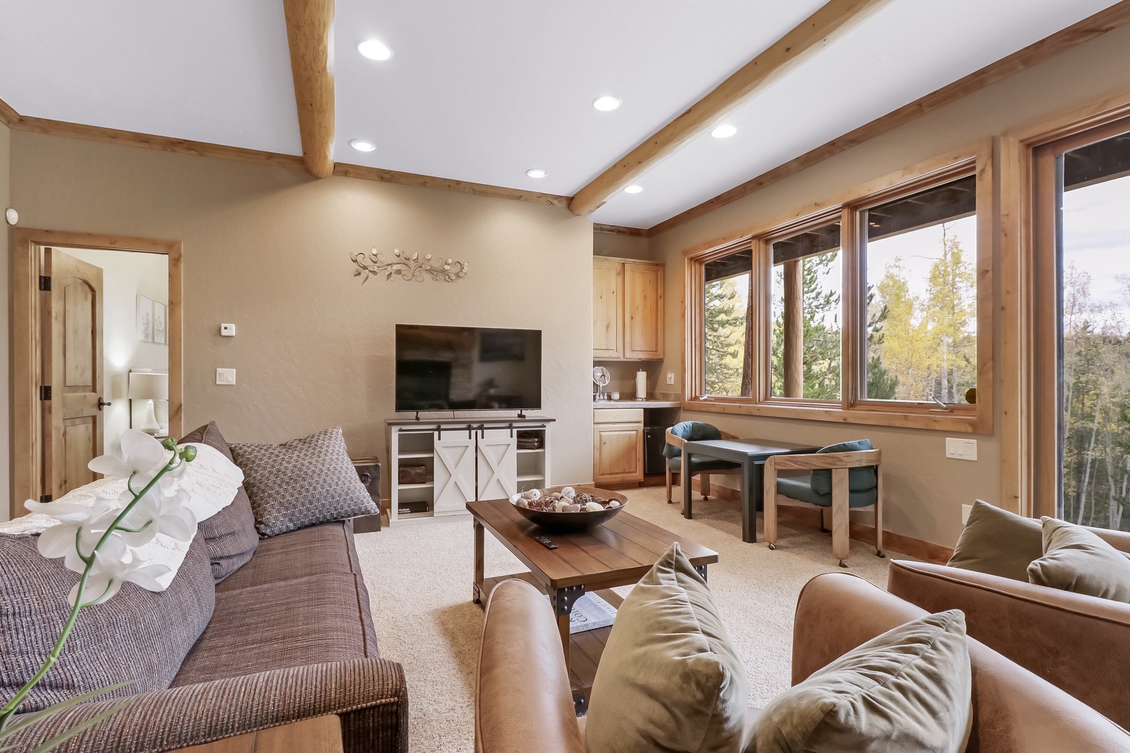Sink into comfortable seating where natural light pours through large windows, revealing peaceful forest views that frame your mountain retreat perfectly.