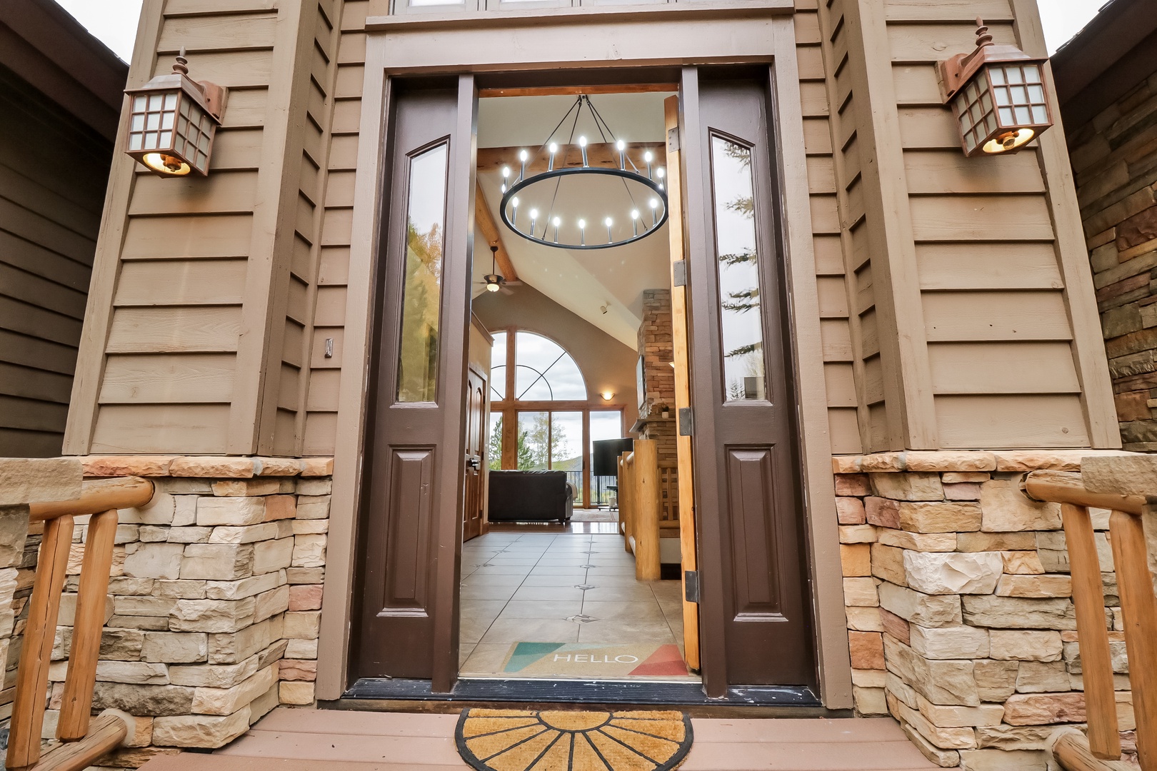 The stone accents and warm lighting frame a welcoming entrance that leads directly into an open, airy interior with vaulted ceilings and thoughtful design touches.