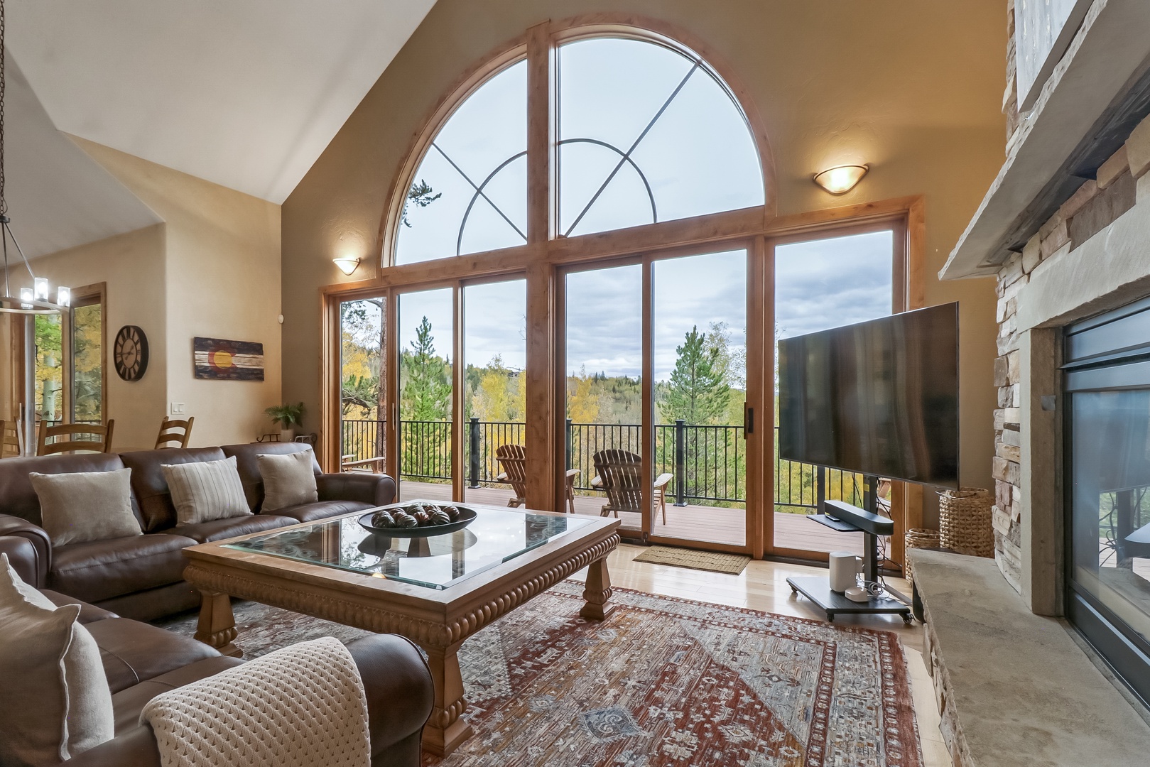 Settle into this airy living room where soaring windows frame sweeping natural views and soft lighting invites you to unwind in comfort.
