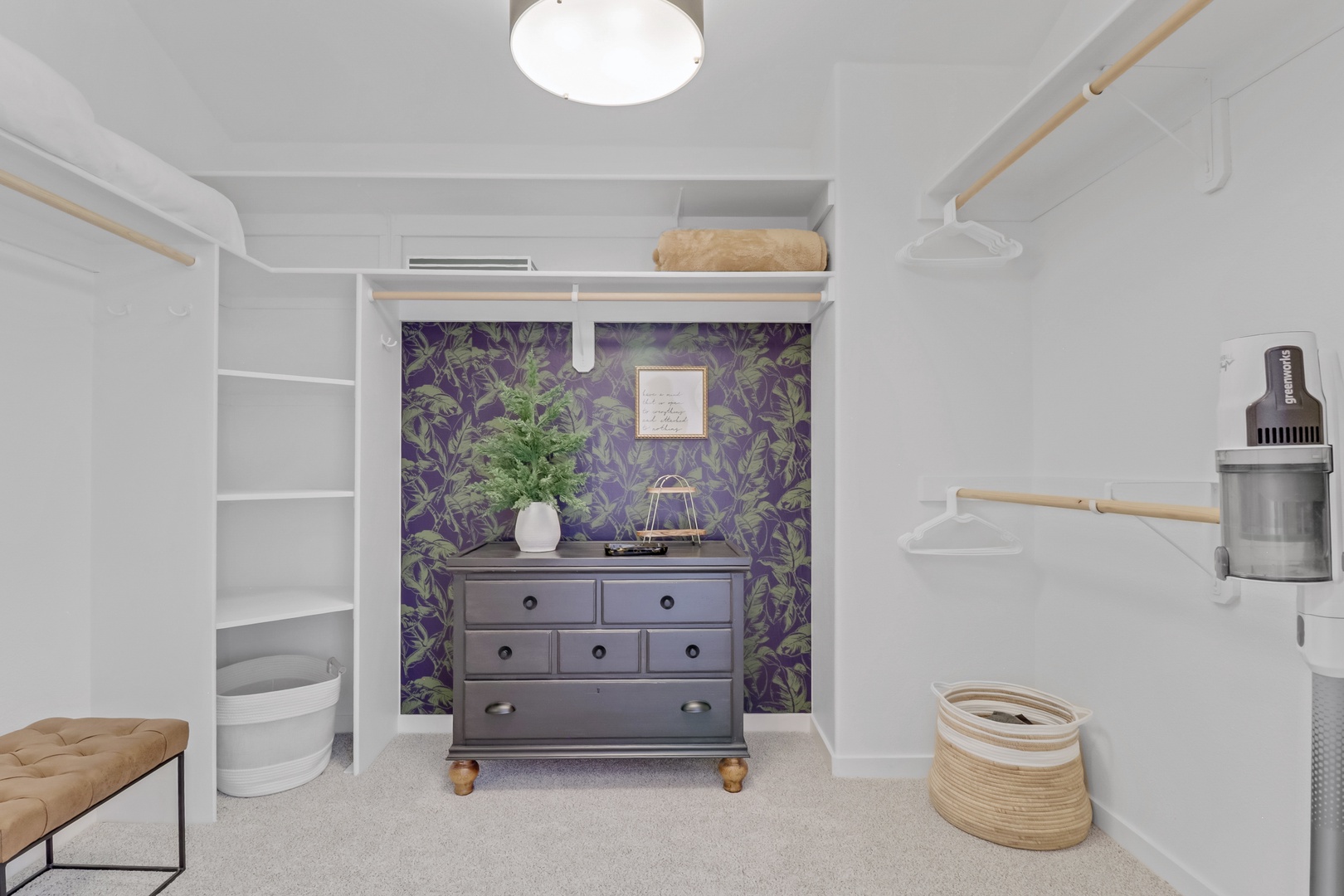 Your spacious walk-in closet offers abundant storage with custom shelving, elegant purple botanical wallpaper, and a vintage dresser.