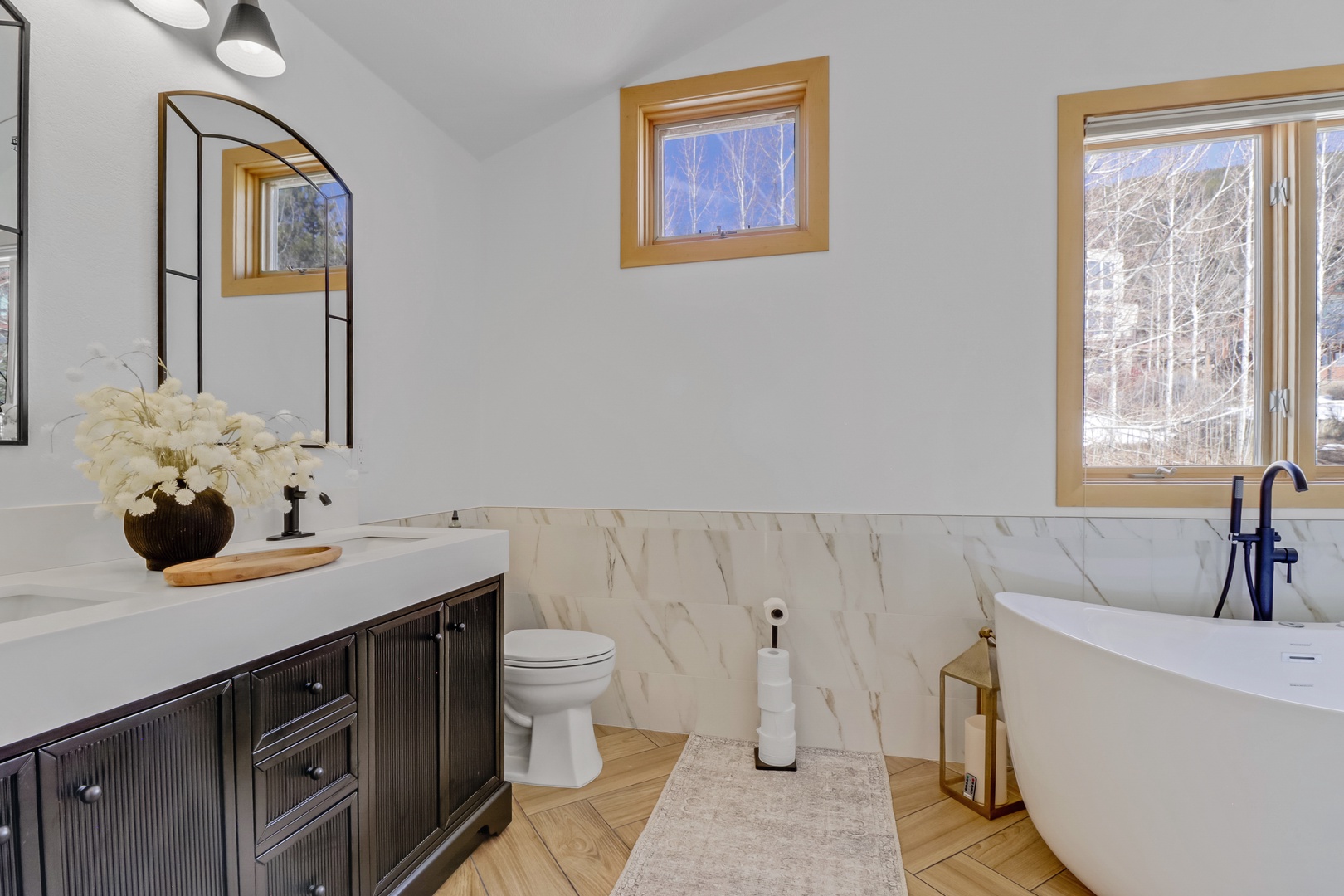 Soak in your luxurious freestanding jetted tub while gazing at winter landscapes through large windows in this elegant bathroom.