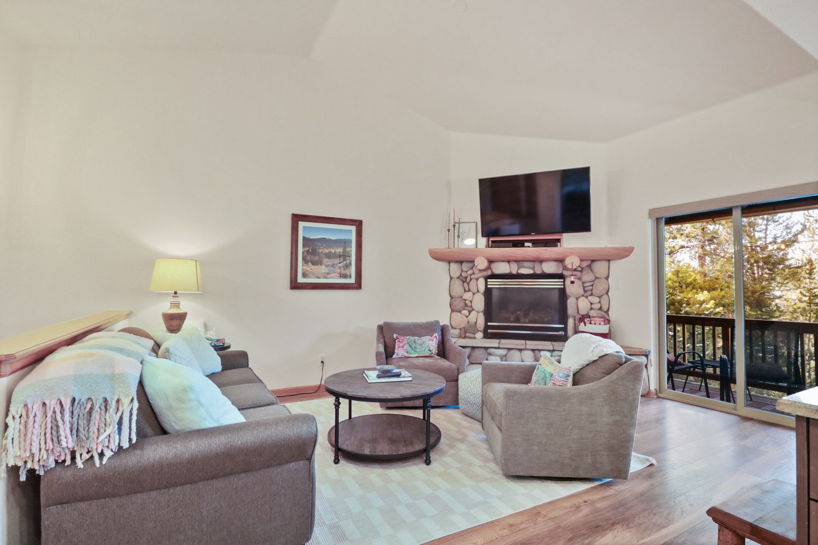 Cozy up in your living room with stone fireplace, plush seating, and peaceful balcony views.