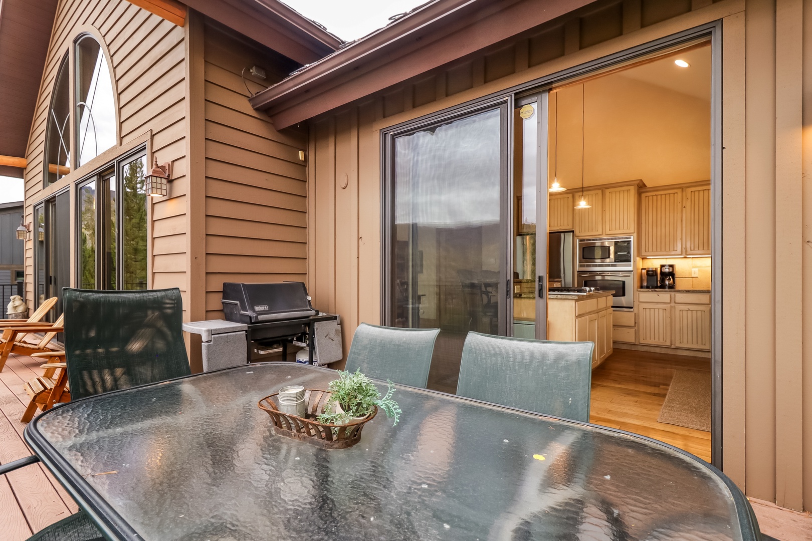 Step onto your private deck where a spacious dining table and grill await. Large sliding doors open directly into a bright, fully-equipped kitchen—perfect for easy indoor-outdoor living and mountain-air meals.