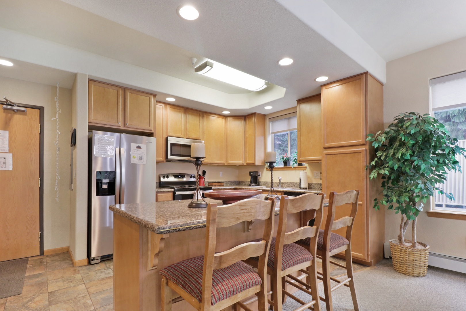 You'll love cooking and gathering in this bright, fully equipped kitchen with a breakfast bar, stainless appliances, and warm wood cabinetry—perfect for your vacation meals.