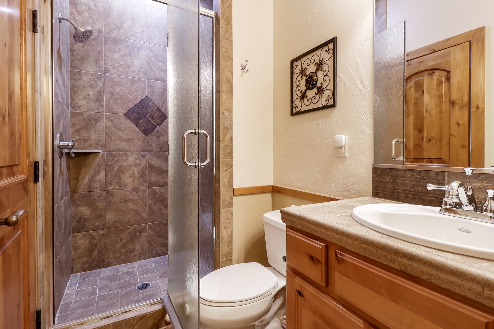Step into your private bathroom with elegant stone finishes, a spacious walk-in shower, and warm wood accents that create a cozy, cabin-inspired retreat.