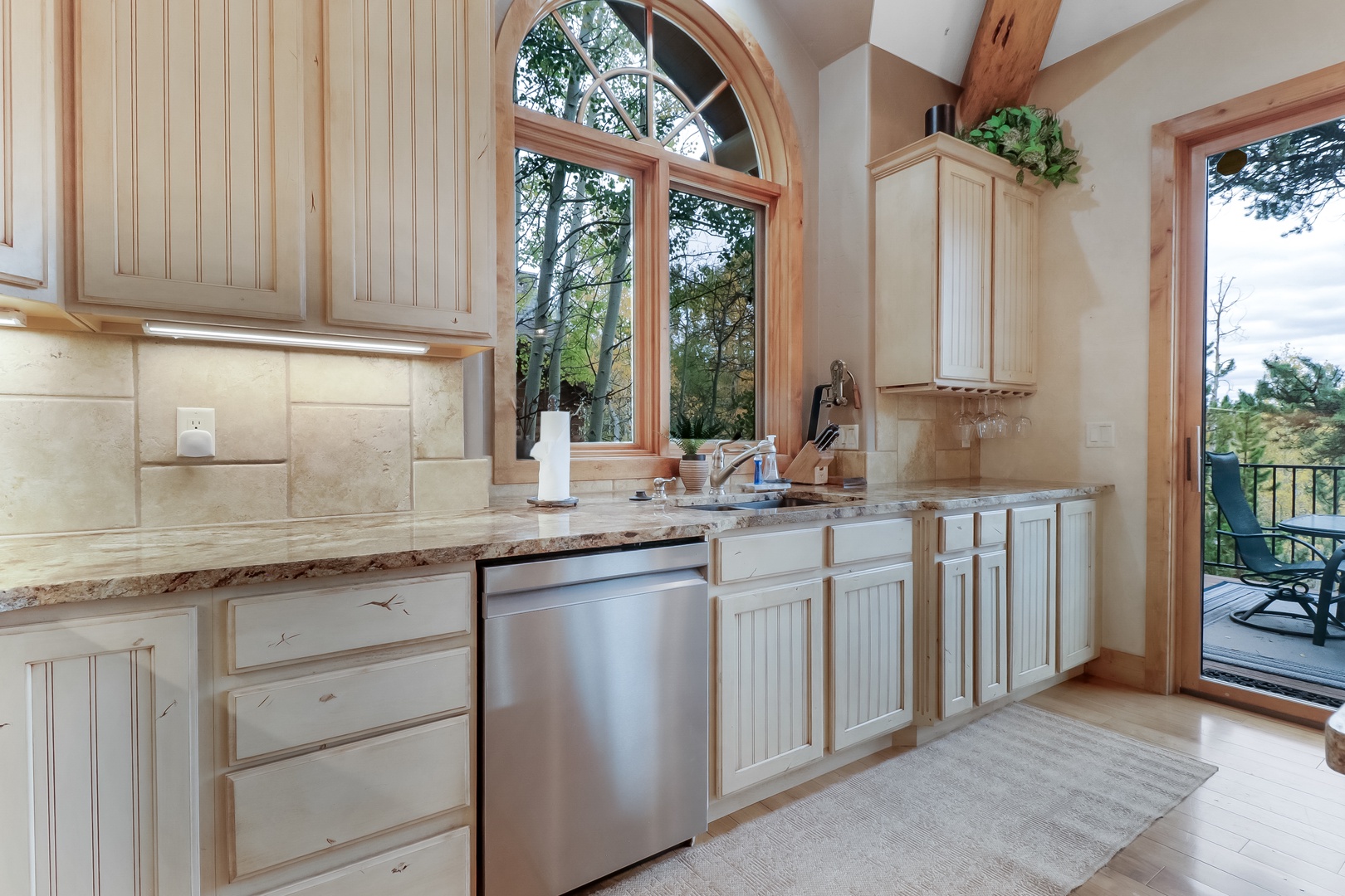 Prepare your favorite meals in this bright, welcoming kitchen with stone counters and lovely views of the surrounding trees. The soaring arched window fills your space with natural light while you cook.