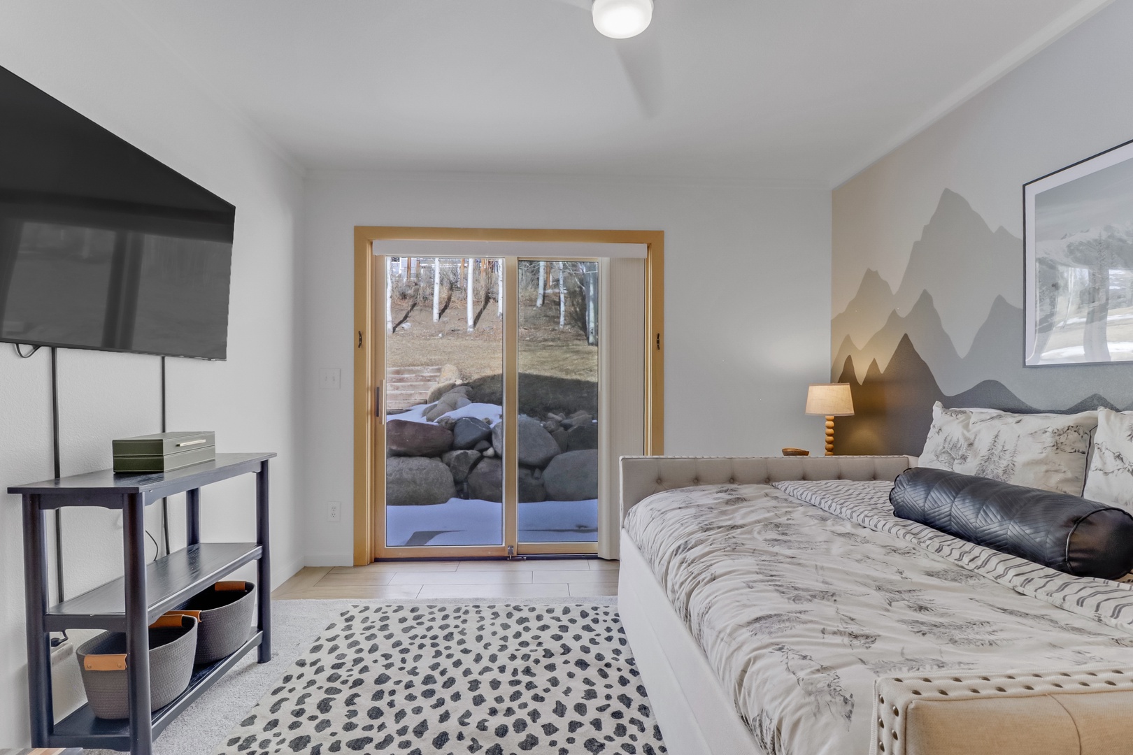 Drift off in your mountain-themed bedroom with sliding doors opening to natural stone features and forest views.