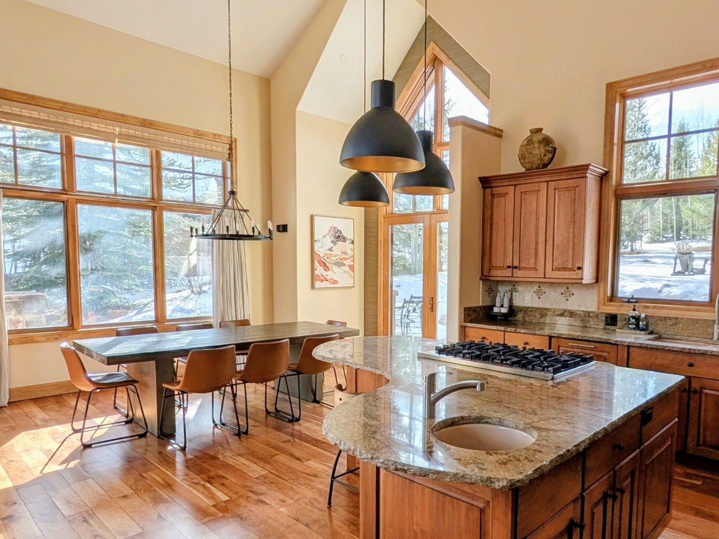 Large open concept dining and kitchen area with updated lighting. The home features large windows throughout, allowing ample natural light to come in