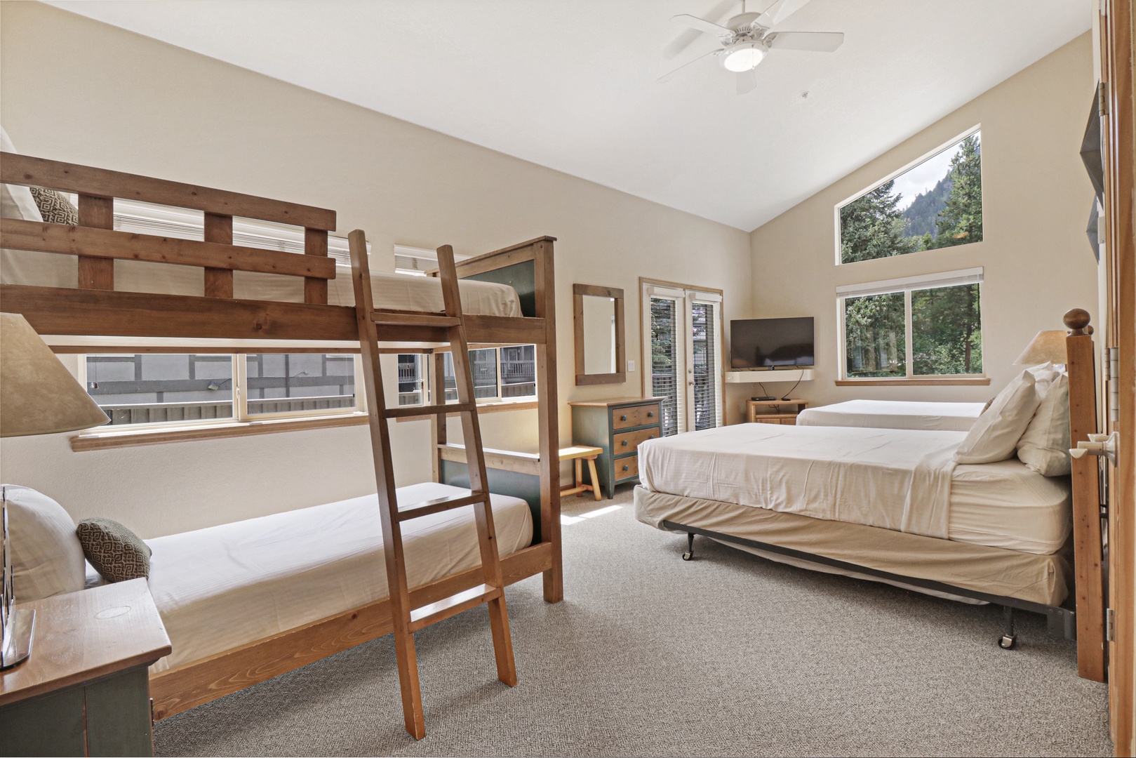 Your group will appreciate this versatile bedroom with bunk beds and additional sleeping space, offering flexibility for families or friends. Natural light fills the room through large windows framing peaceful mountain views.