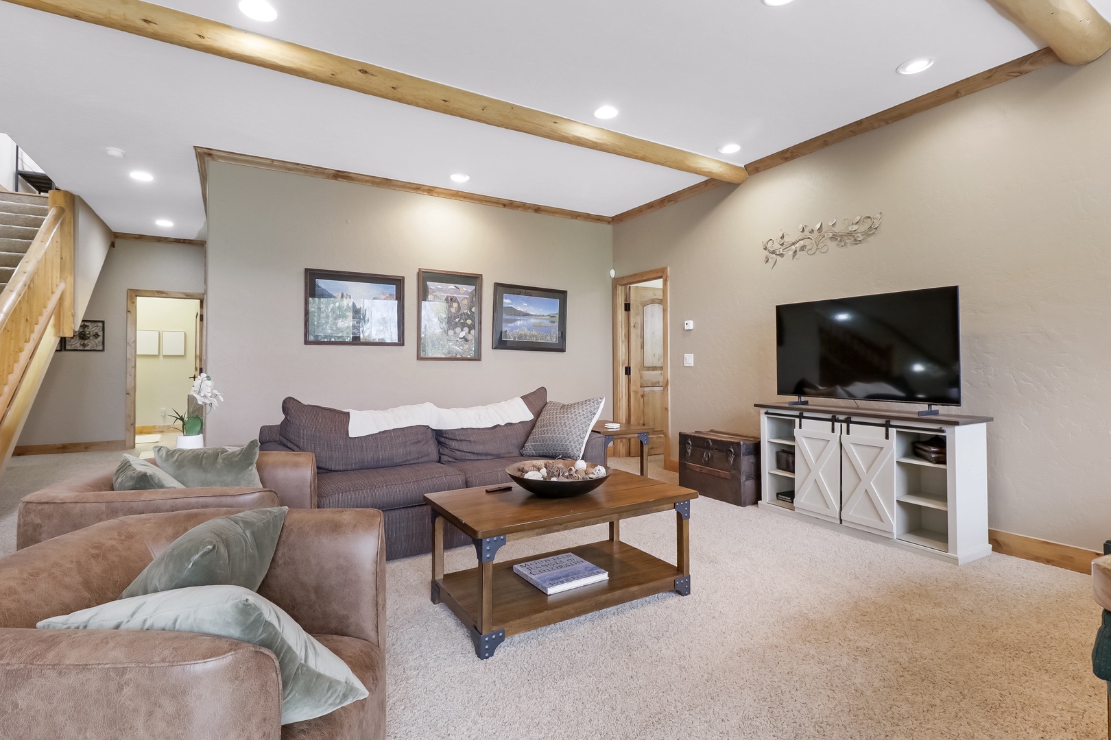 Sink into plush seating and unwind in your spacious living room, where rustic wood beams and warm tones create a cozy mountain retreat atmosphere.