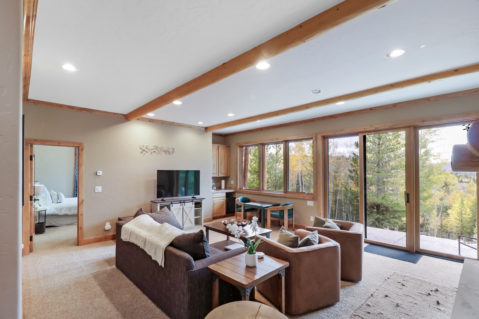 Unwind in your spacious living room, where exposed wood beams frame floor-to-ceiling windows that open to sweeping forest views and your private balcony.