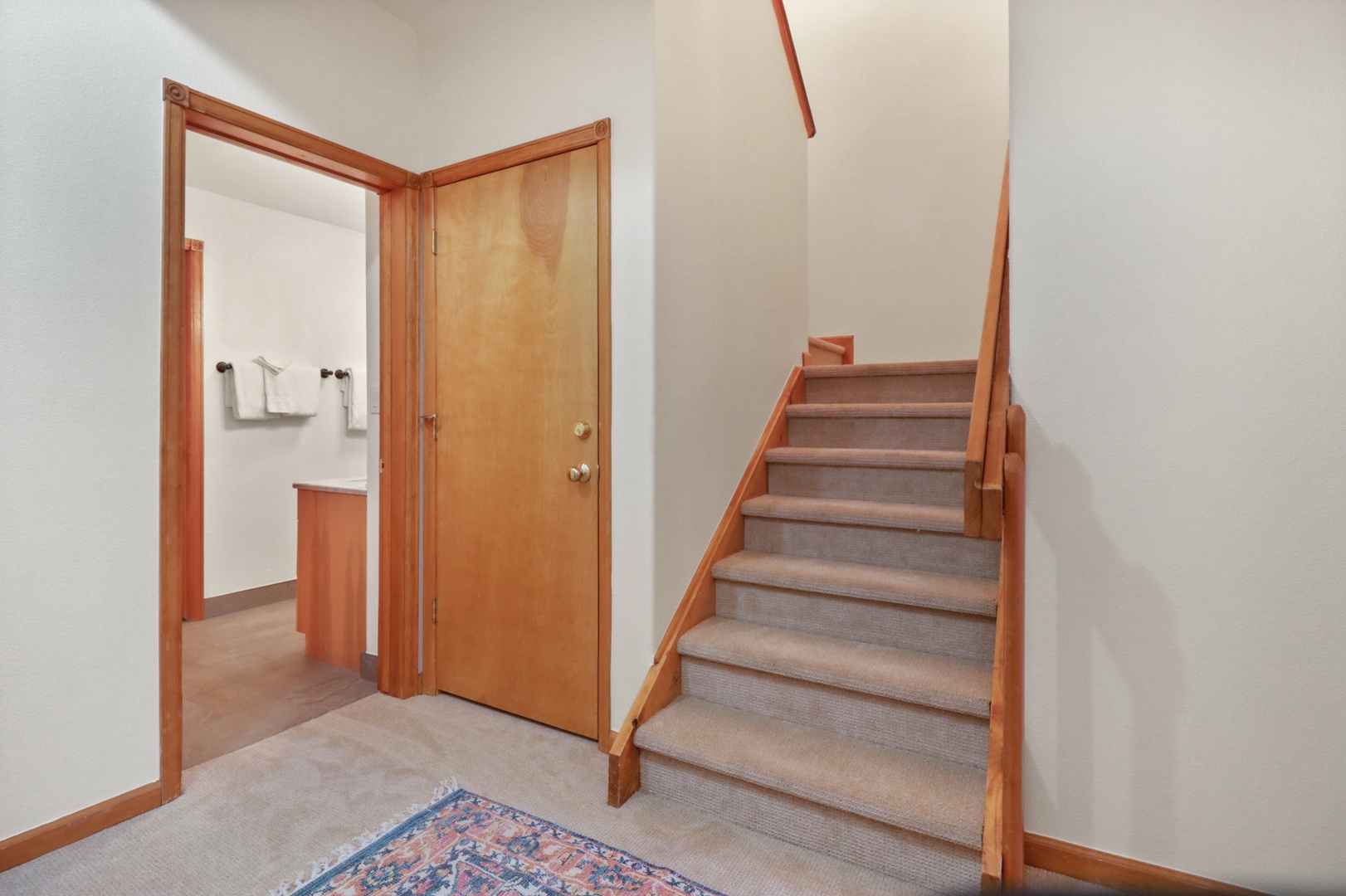 Your home's welcoming entryway features warm wood accents and carpeted stairs leading to your private upstairs retreat.