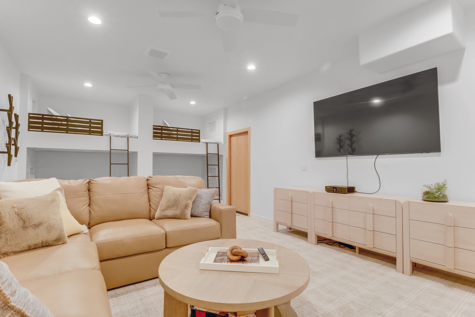 Relax in your stylish living space featuring plush seating, modern entertainment center, and cozy bunk beds for a perfect group getaway.