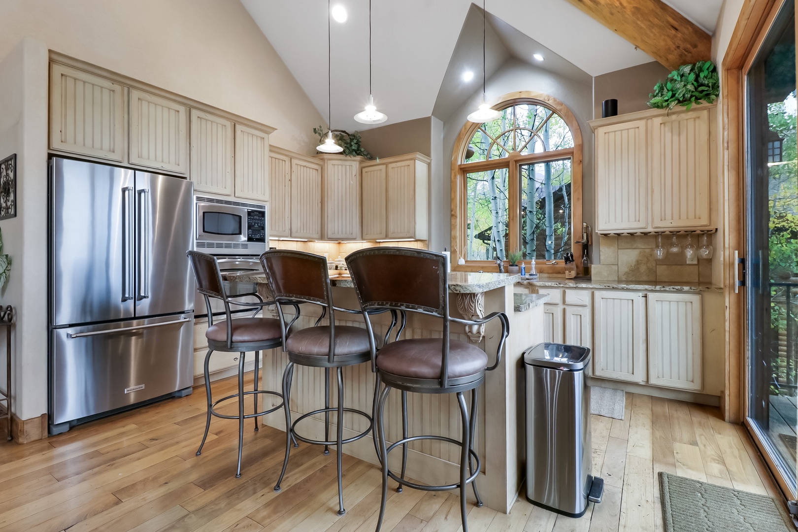 Your gourmet kitchen awaits with stainless steel appliances, a breakfast bar for casual dining, and beautiful natural light streaming through the arched window—perfect for cooking up mountain memories.
