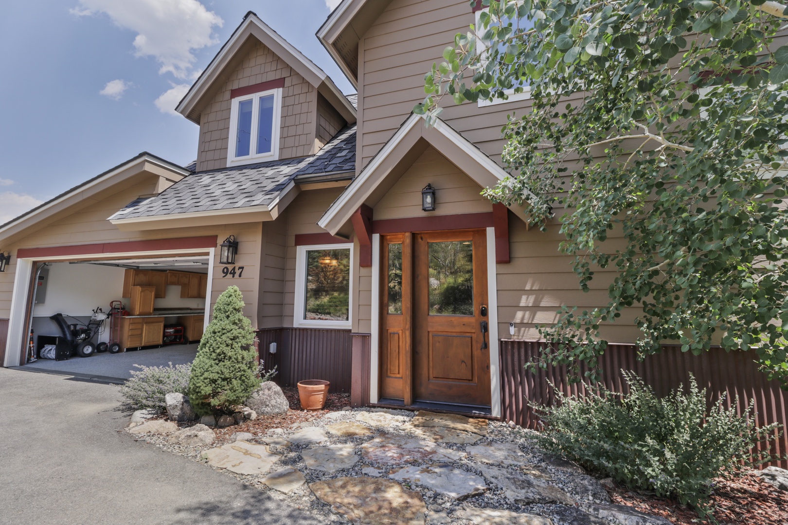 This charming property welcomes guests with a warm, craftsman-style entrance framed by natural stone pathways and mature landscaping. The inviting front door and thoughtful exterior details set the tone for a comfortable mountain retreat.