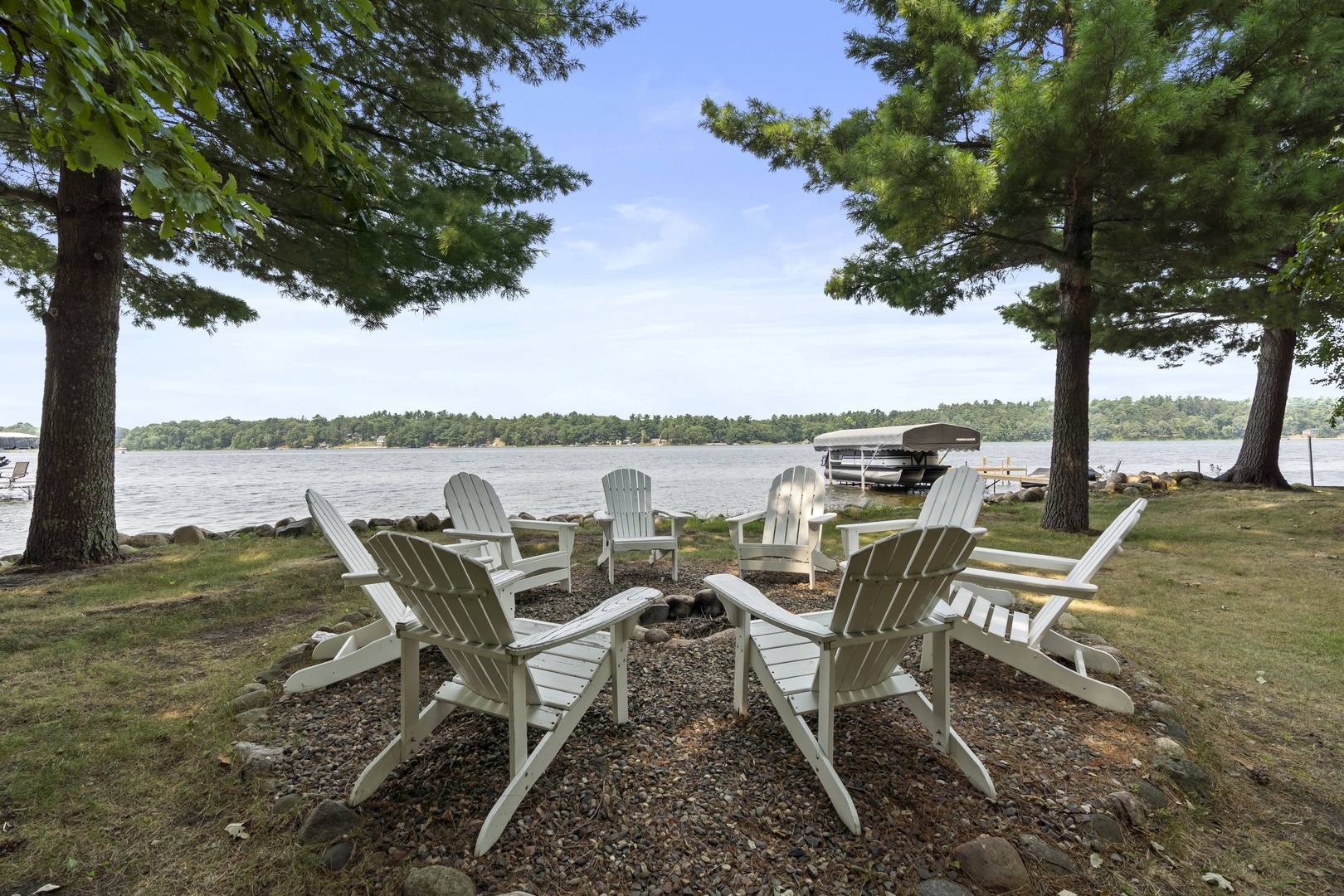 The property features a lakefront location with a circular fire pit seating area, offering direct access to the water and surrounded by natural landscape.