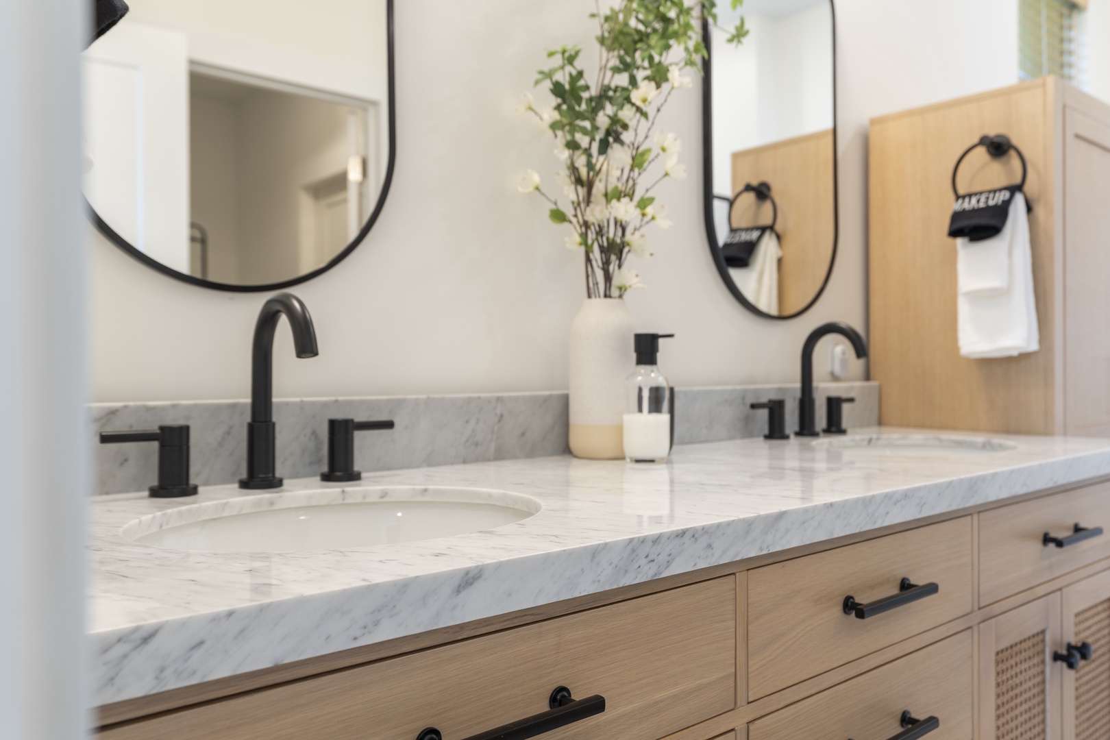 Freshen up in your spa-inspired bathroom, where dual marble vanities, sleek black fixtures, and modern round mirrors create a sophisticated retreat for your morning routine.