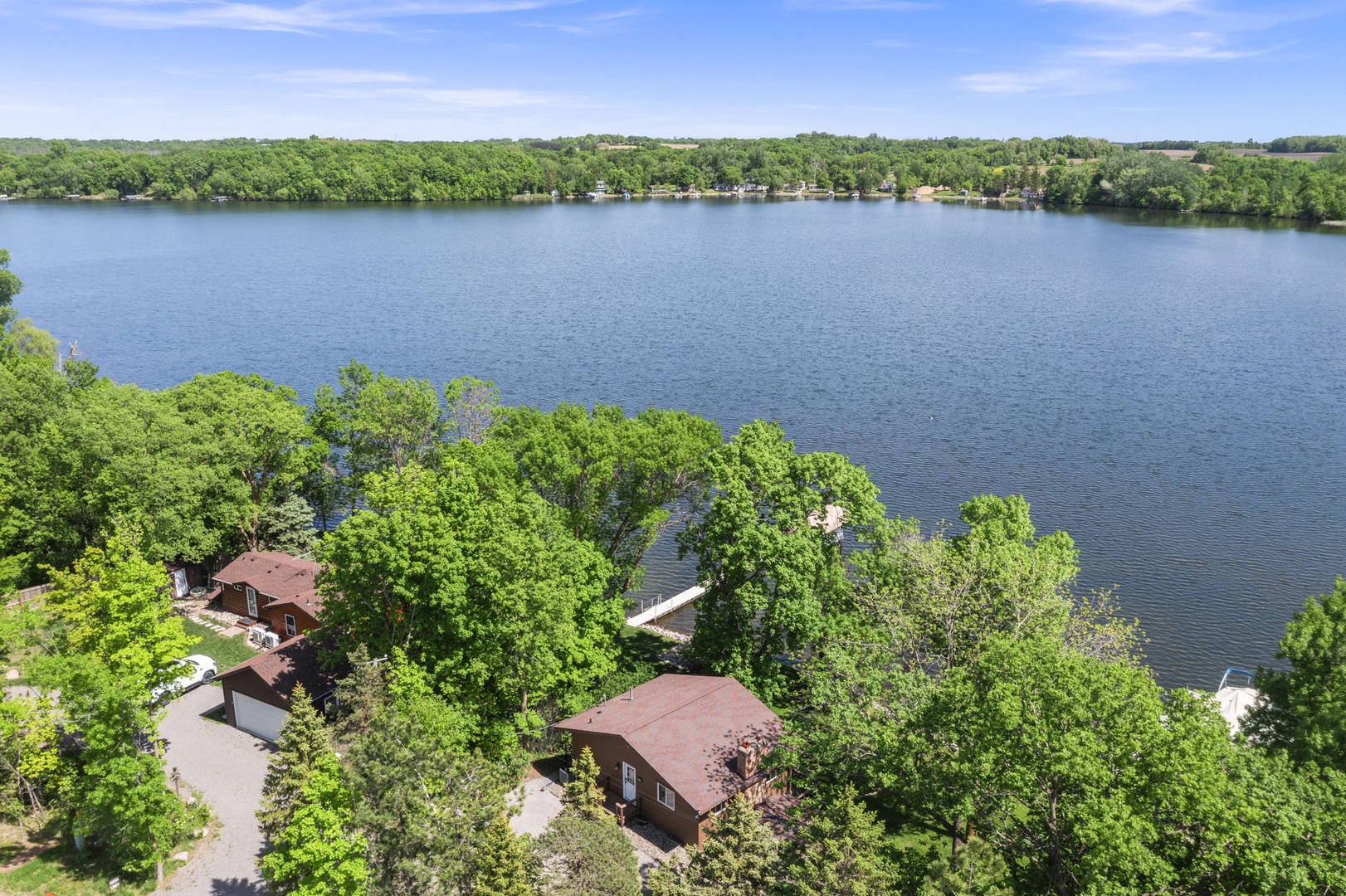 This aerial view reveals the property's private lake setting, surrounded by lush greenery and calm waters, offering a peaceful natural backdrop for your getaway.
