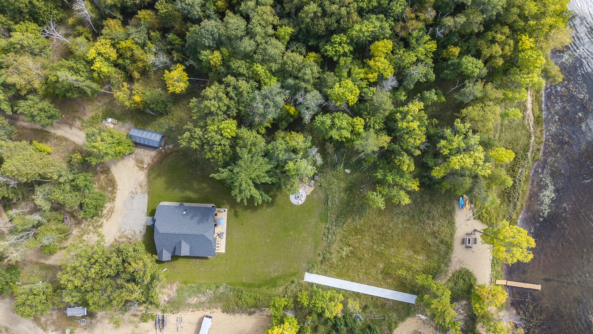Aerial view of a secluded, nature-surrounded property nestled among dense forest and waterfront access.