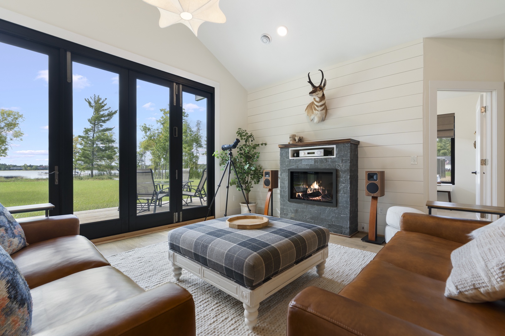Sink into luxurious leather seating by the glowing fireplace while gazing out at peaceful lakefront views through floor-to-ceiling glass doors. This stylish retreat blends rustic charm with modern comfort, creating your perfect escape.
