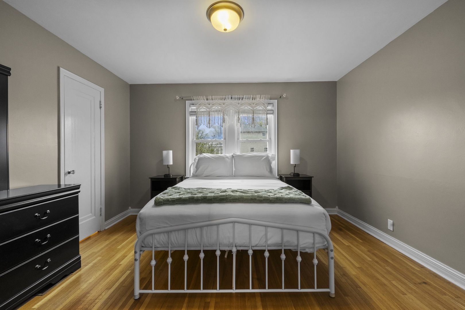 Sink into crisp white linens and unwind in your peaceful bedroom, where warm wood floors and soft lighting create the perfect retreat after exploring.