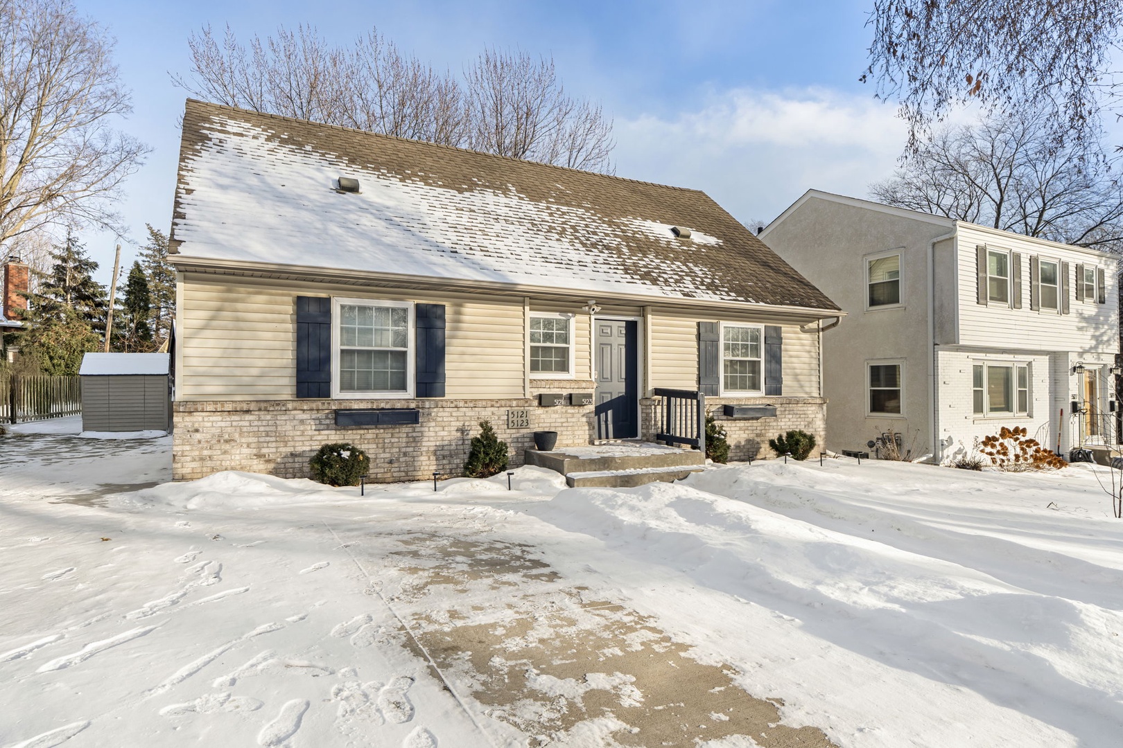 Charming winter retreat with snow-covered grounds and cozy brick-and-siding exterior, nestled in a peaceful residential neighborhood.