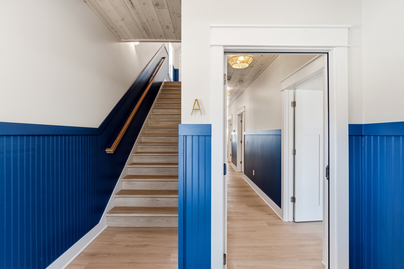 Unit A main level entryway with blue wainscoting staircase and hardwood floors