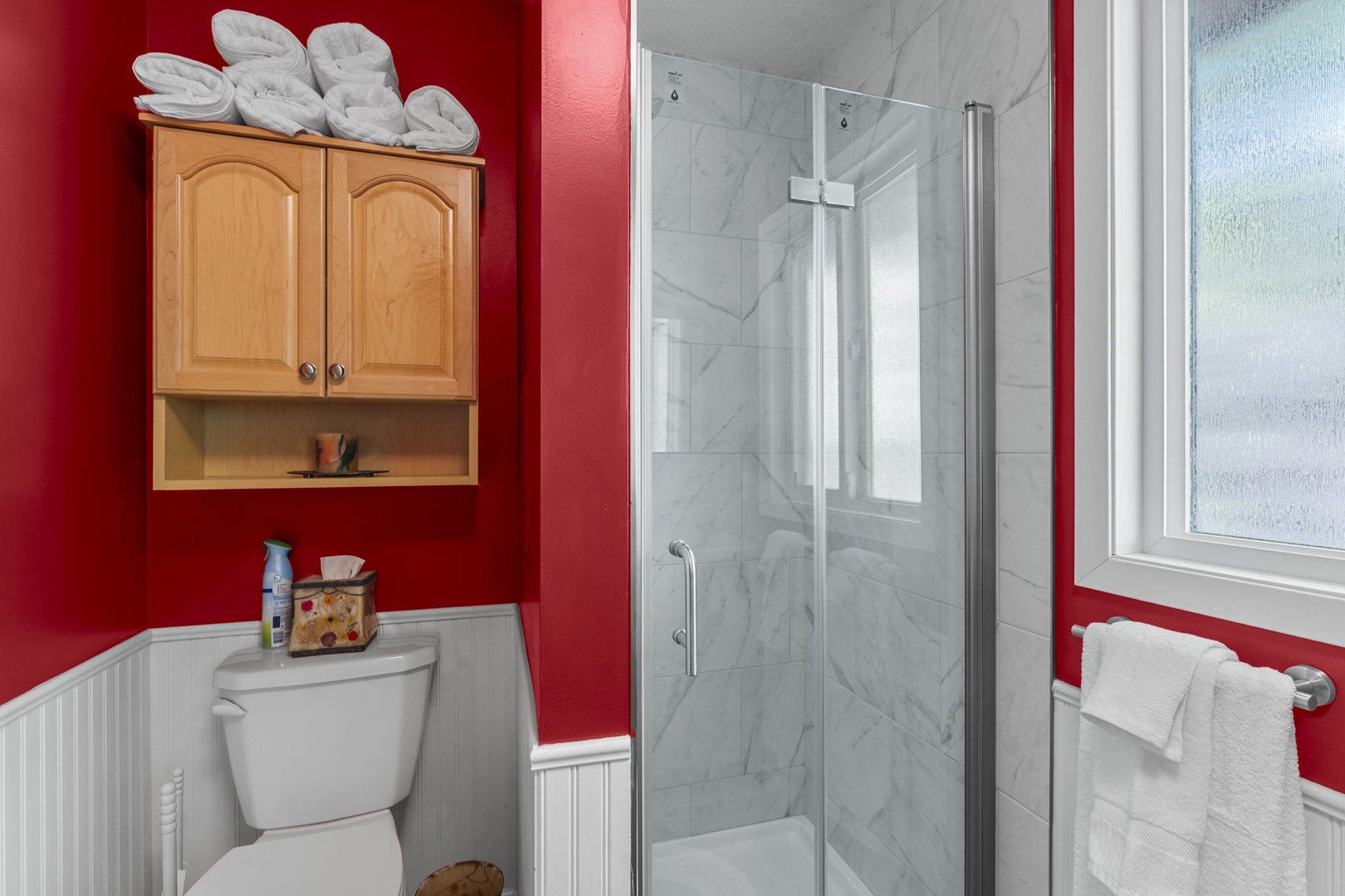Your private bathroom features a spacious walk-in shower with elegant marble-style tile, plush towels, and handy storage to keep your essentials close at hand.