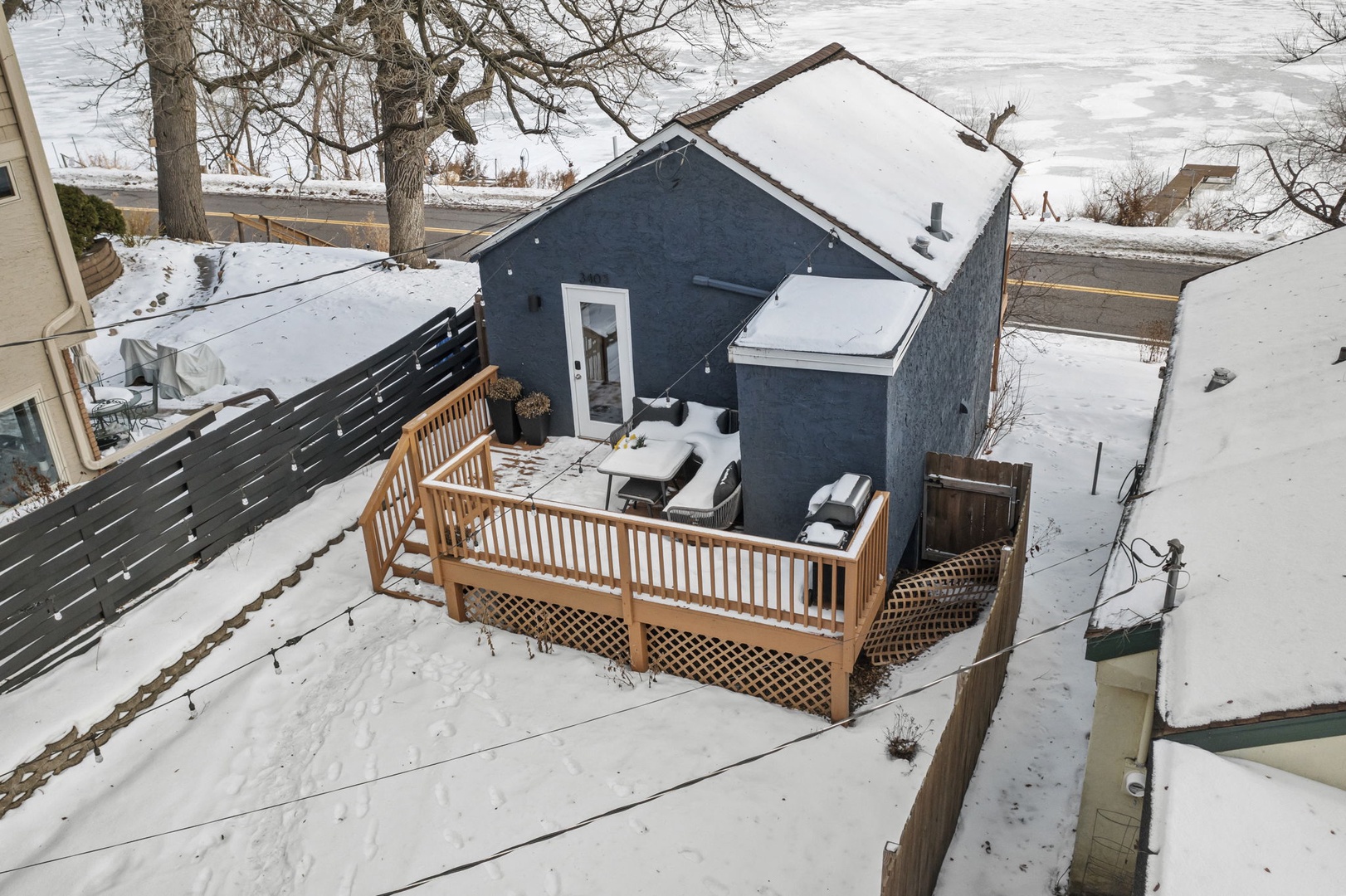 Charming blue cottage with wooden deck nestled in peaceful winter setting.