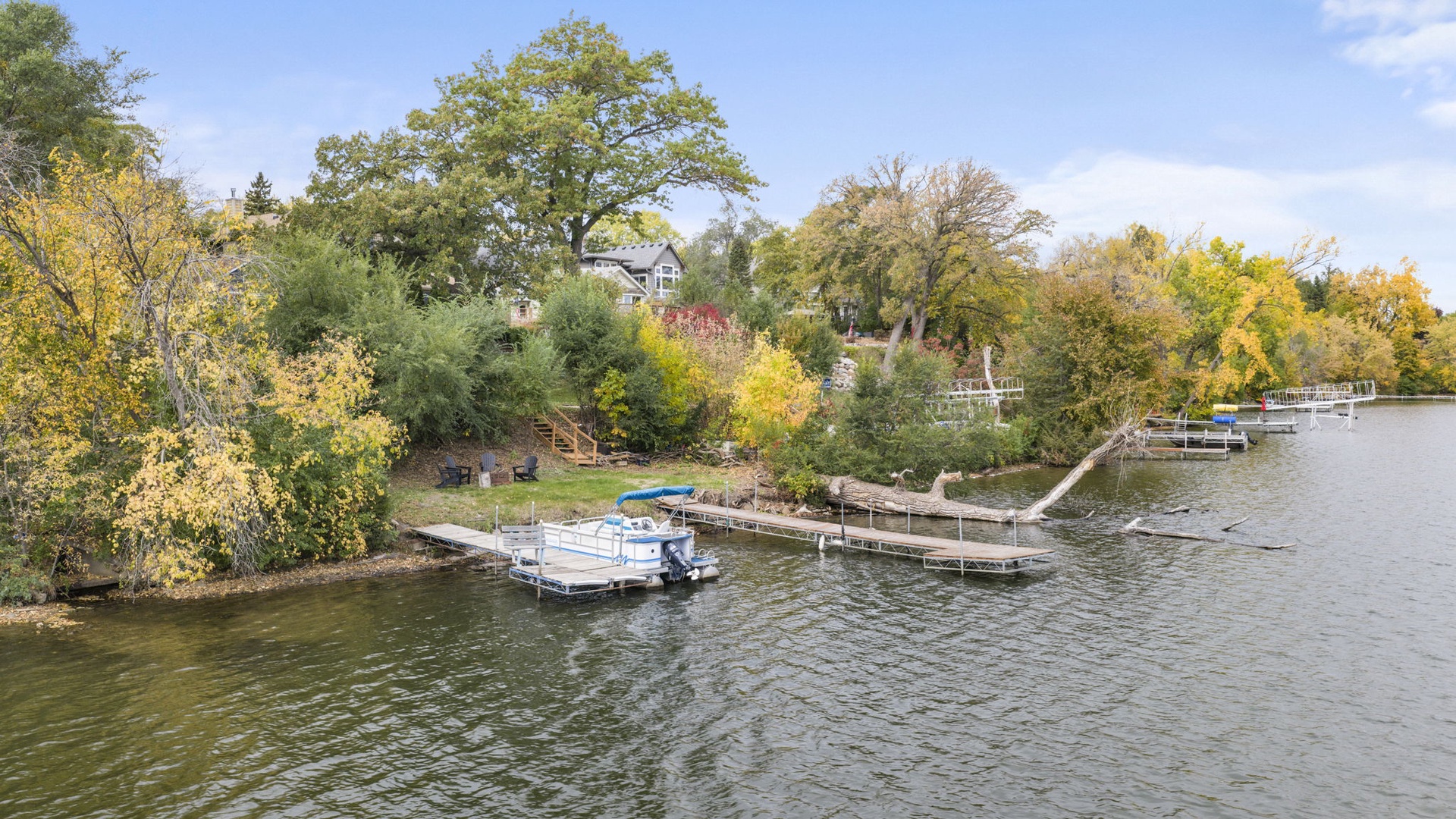 Waterfront property nestled among vibrant autumn foliage with private dock and boat access on a serene river.
