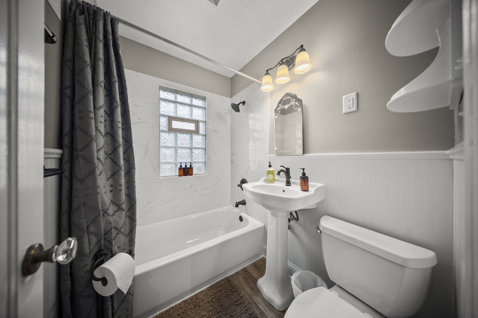 Your private bathroom features a soaking tub, modern fixtures, and natural light. Marble-style tiles and soothing gray tones create a serene space for relaxation.