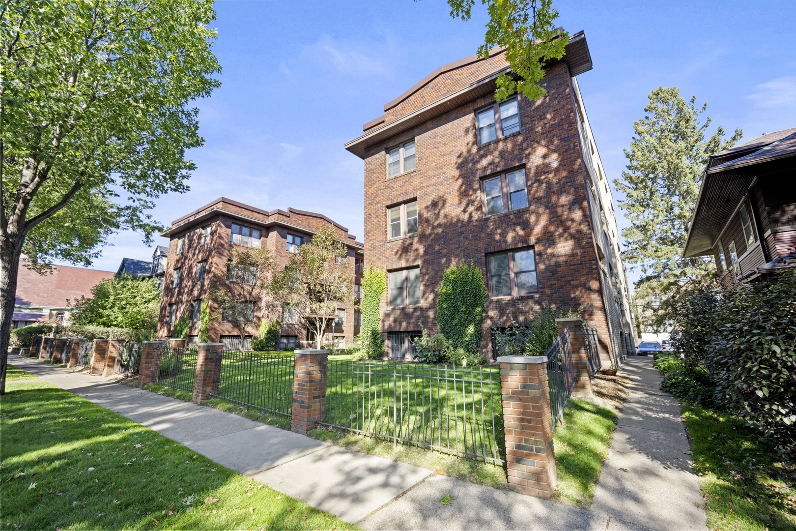 A charming brick building nestled in a tree-lined neighborhood, offering classic architectural appeal with manicured lawns and peaceful surroundings for your stay.