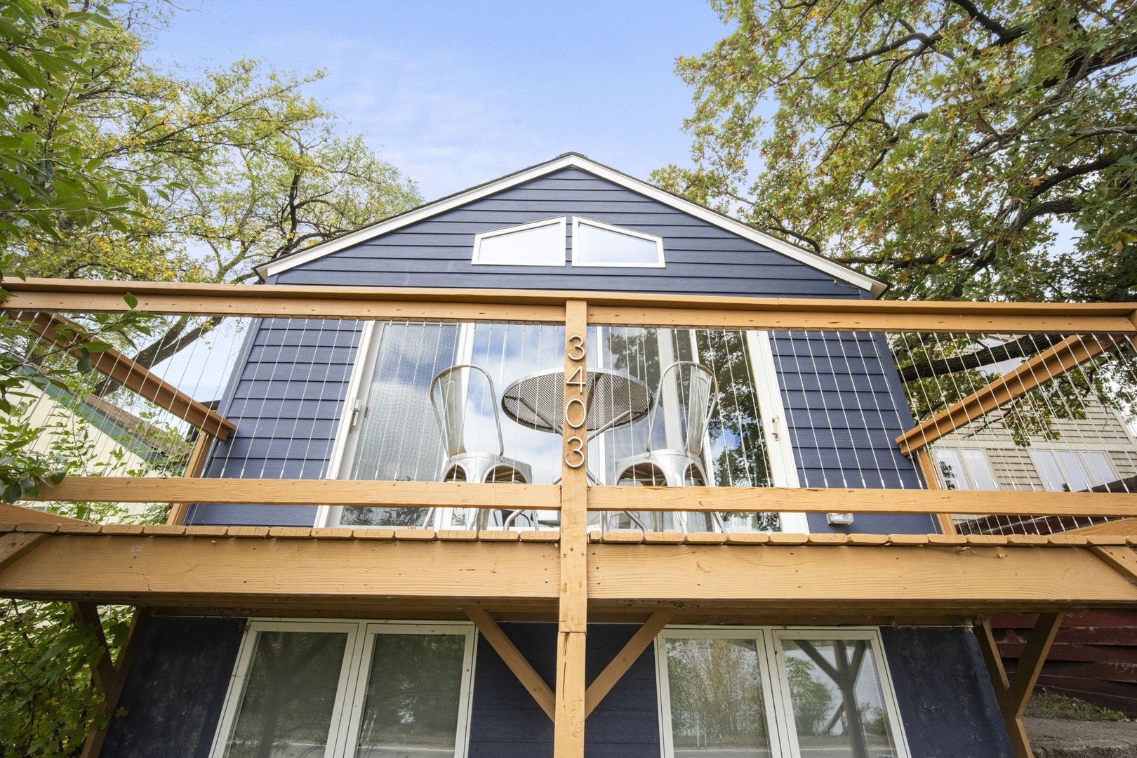 Exterior view of the property nestled among mature trees, featuring deck space and natural wood accents.