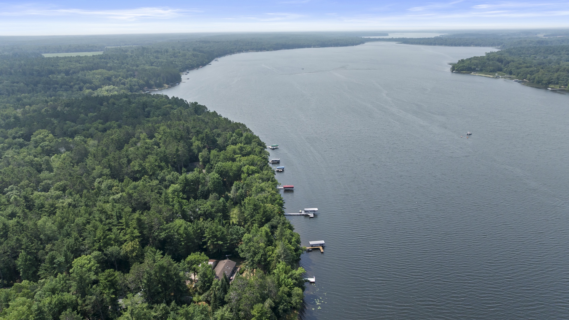 Aerial view of a pristine lakeside property nestled among lush forests, with private boat docks extending into calm waters—an idyllic retreat for nature lovers and water enthusiasts.
