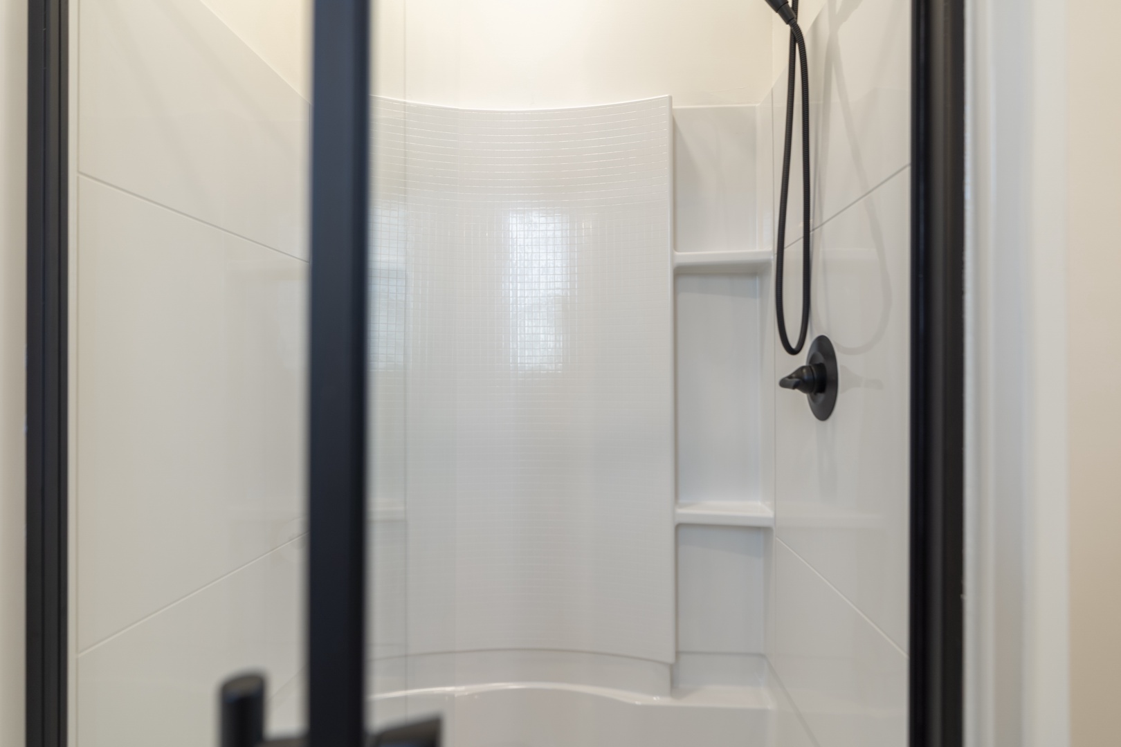 Step into a pristine shower with built-in shelving and modern fixtures, perfect for unwinding after your day of adventure.