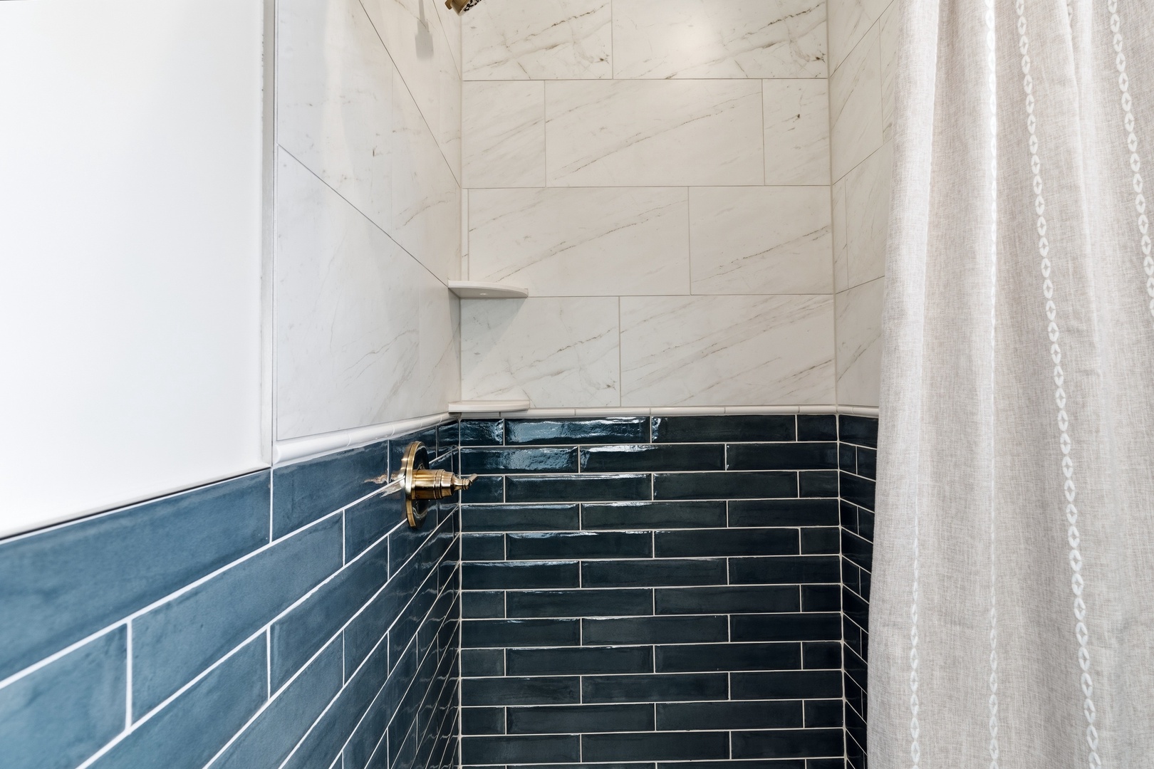 Walk-in shower with marble and blue subway tile