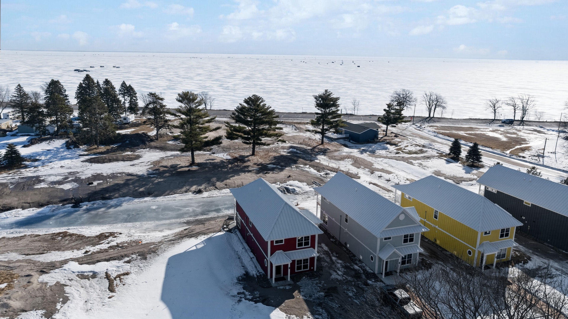 Aerial view of lakefront neighborhood with colorful cottages and frozen bay