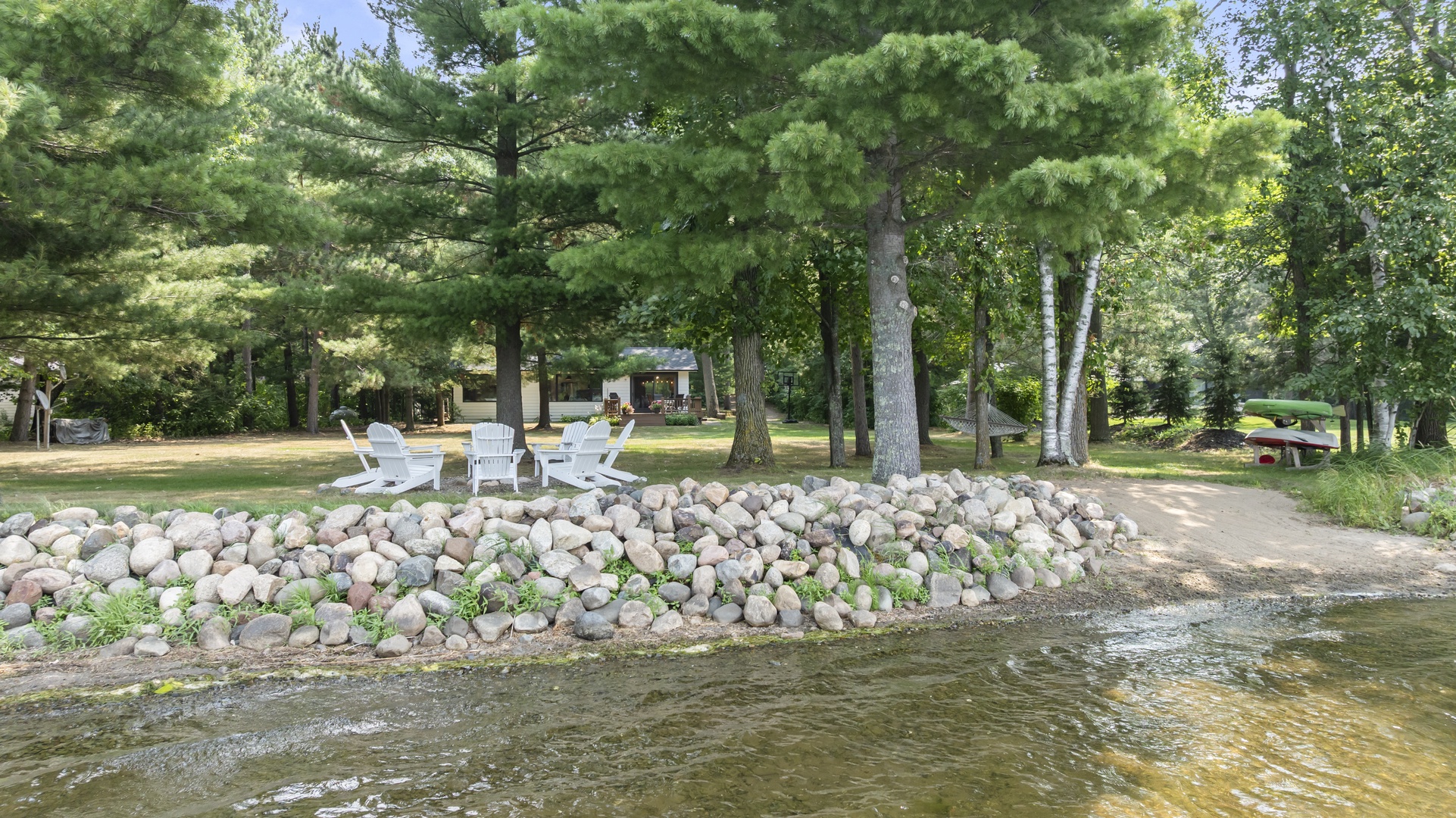 Your own private lakeside retreat awaits, with Adirondack chairs nestled under towering pines and a gentle shoreline just steps away.